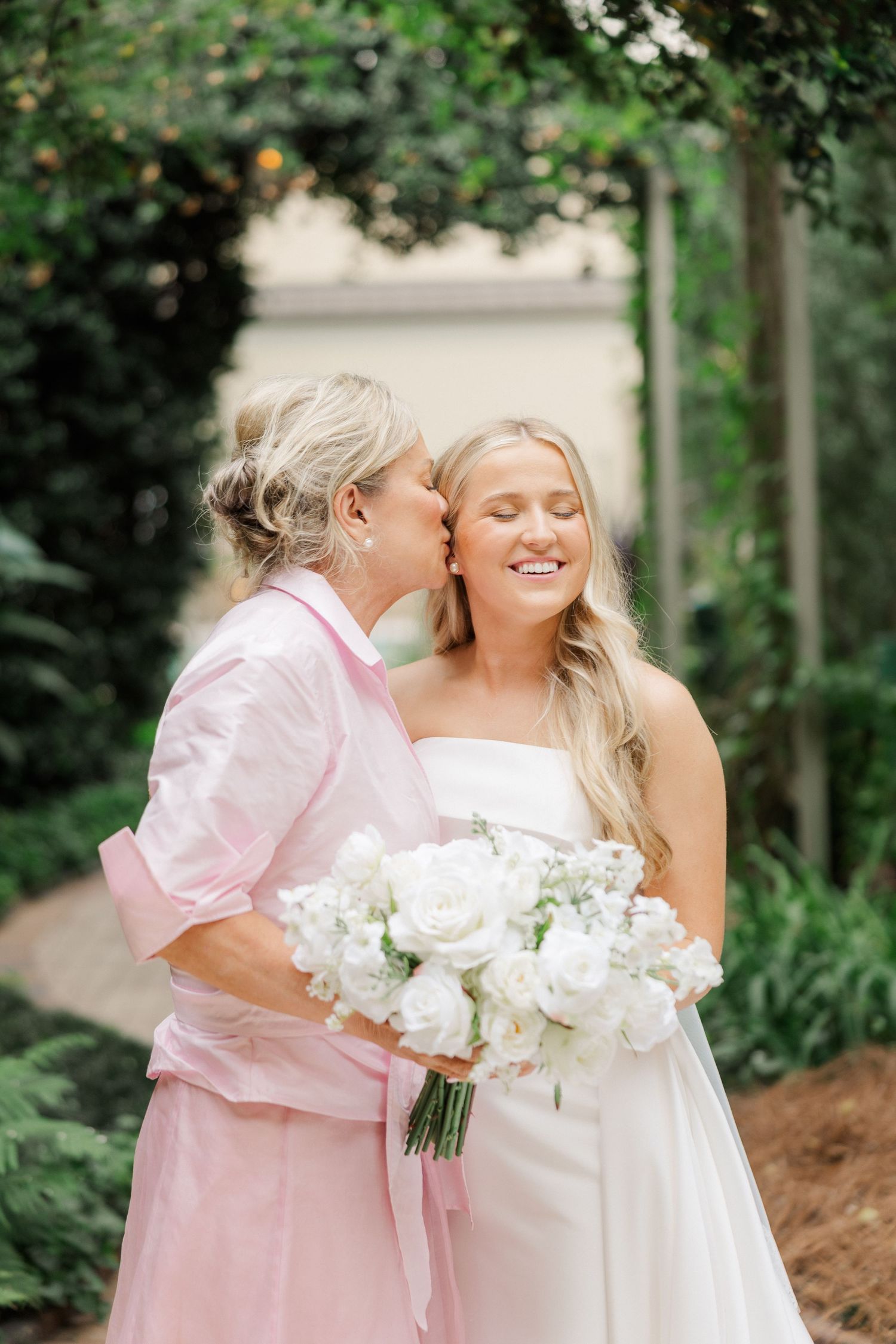 A tender moment between two people at a wedding with white roses and pink attire.