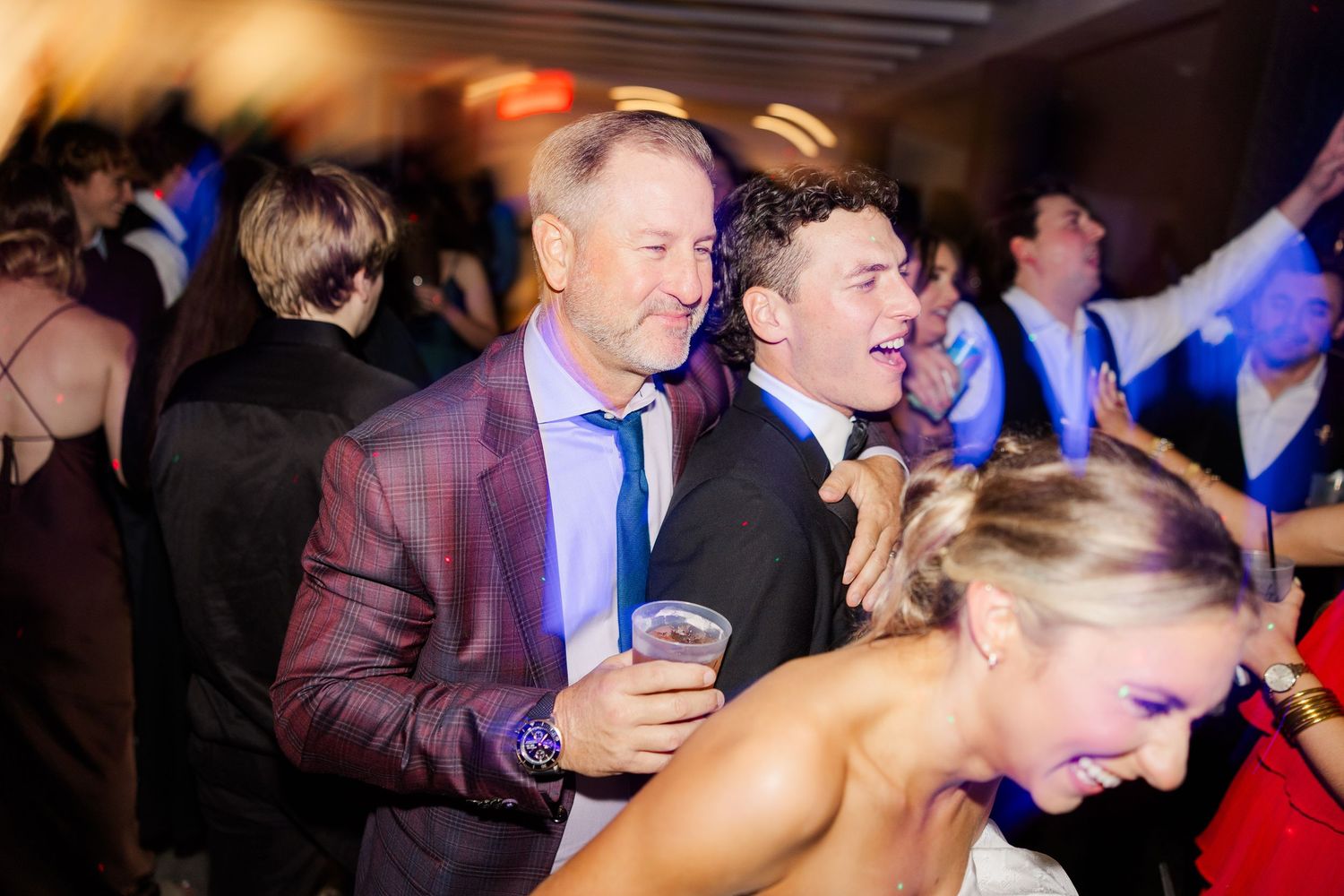 Wedding reception dance floor filled with joyful celebration and colorful lighting.