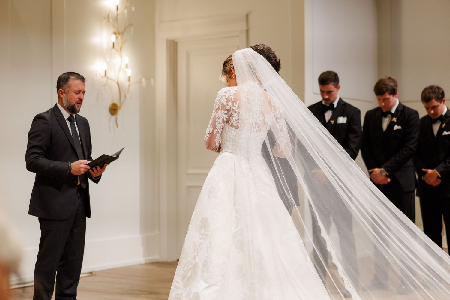 Wedding ceremony in an elegant white ballroom with crystal chandeliers.