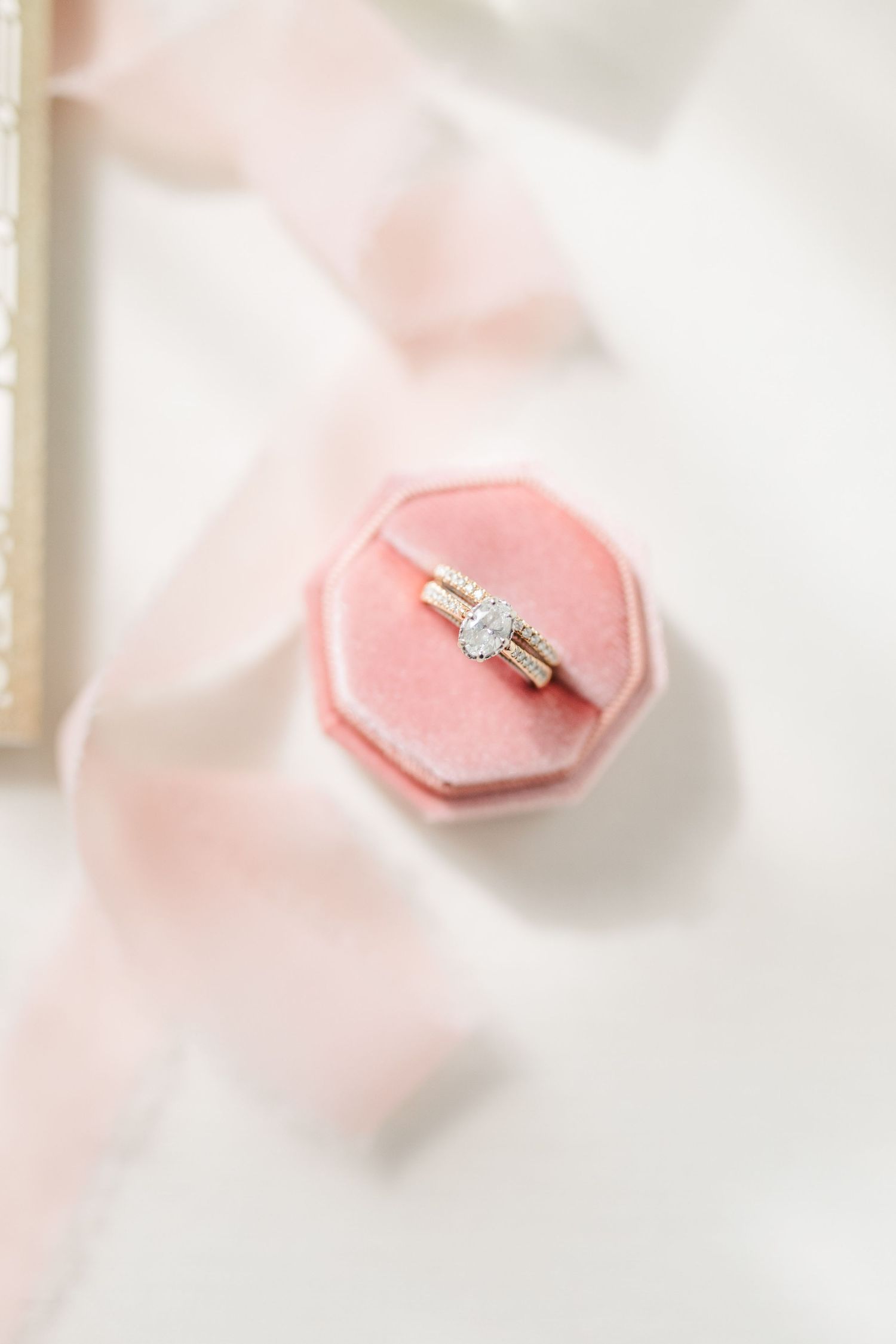 Diamond engagement ring sits elegantly on a pink velvet octagonal ring box.