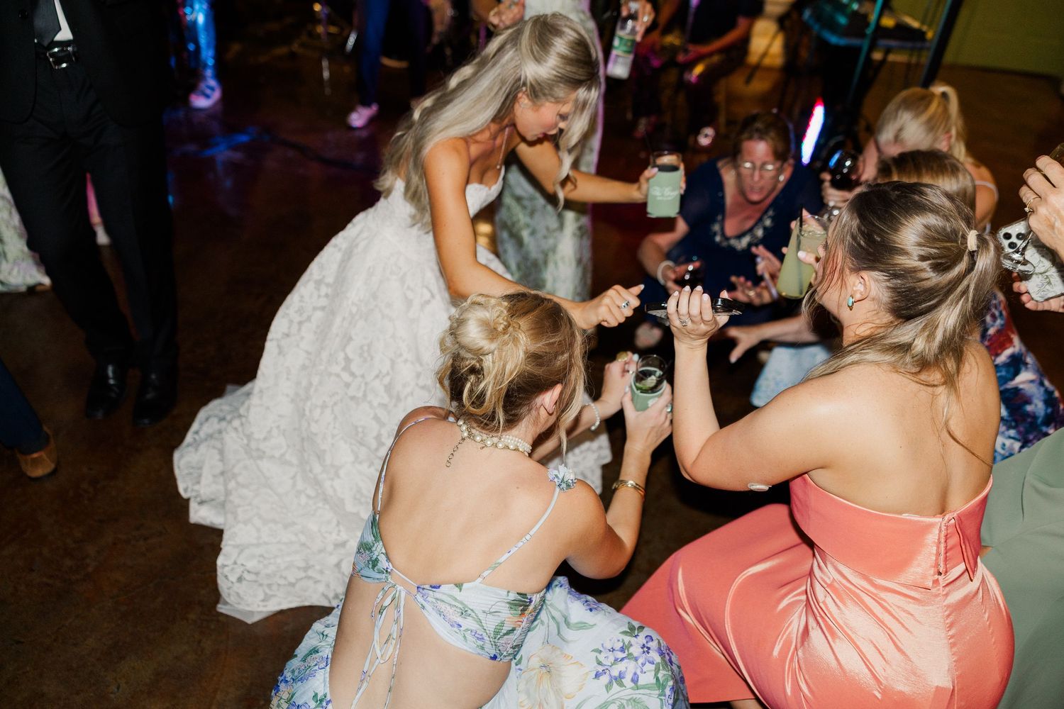 Bride celebrates on the dance floor with bridesmaids during lively wedding reception party.