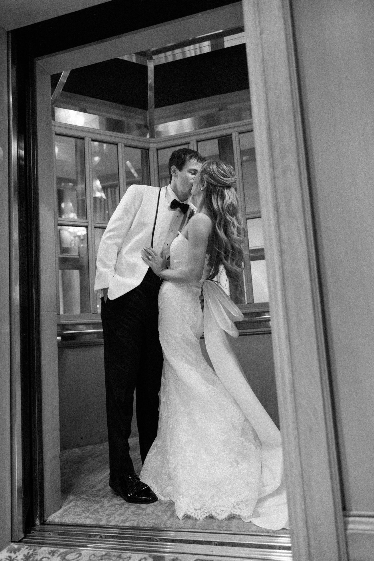 Black and white photo of newlyweds sharing a romantic moment in a hallway.