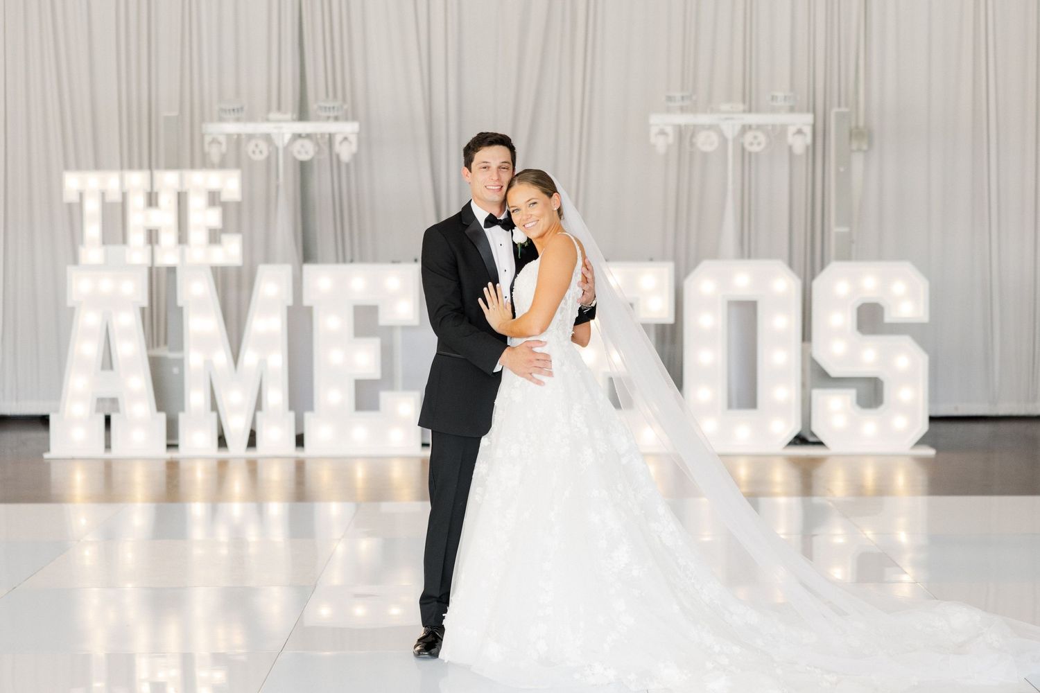 Modern wedding reception space with illuminated letter decorations spelling out text.