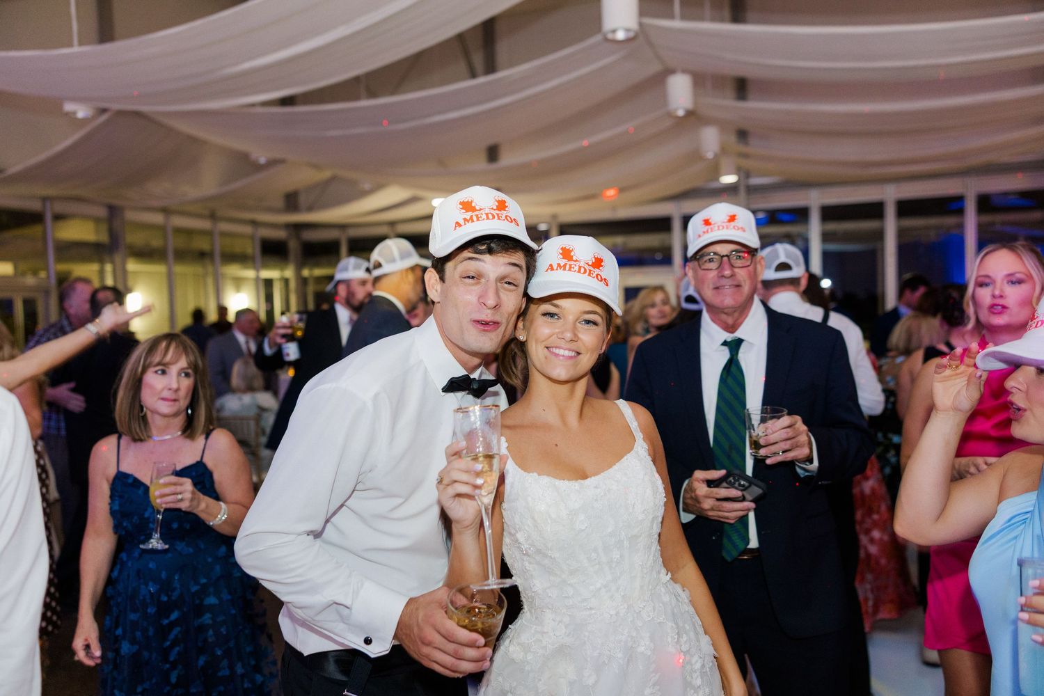 Wedding reception party with guests dancing and celebrating under draped ceiling.
