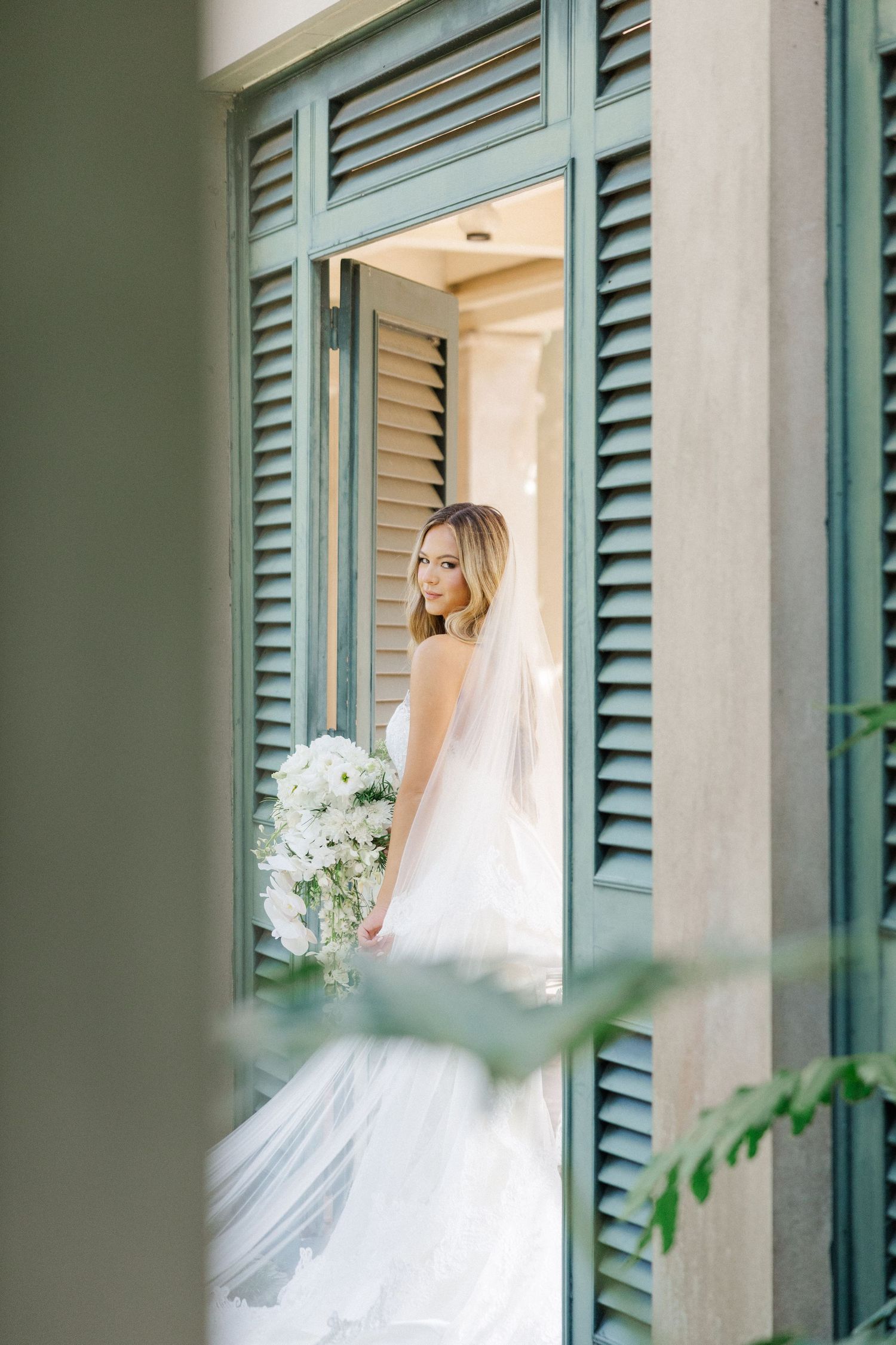Dreamy bridal portraits captured against turquoise shutters and white pillars.