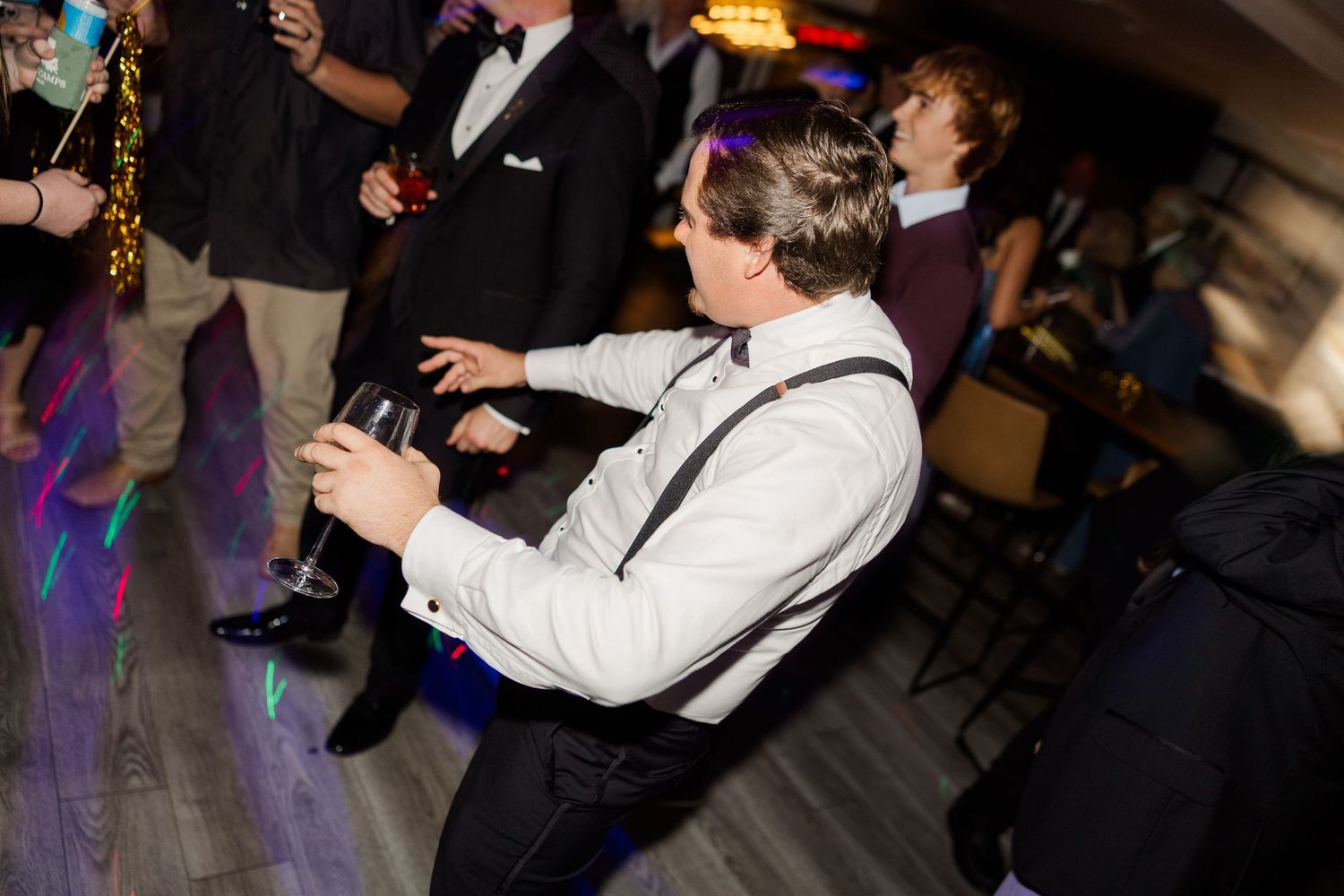 Wedding reception dance floor with guests celebrating under party lights.