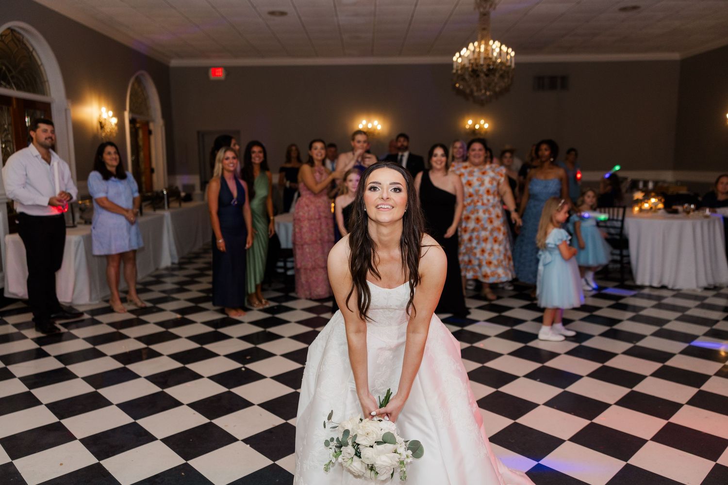 Wedding celebration on a black and white checkered dance floor with guests enjoying the festivities.