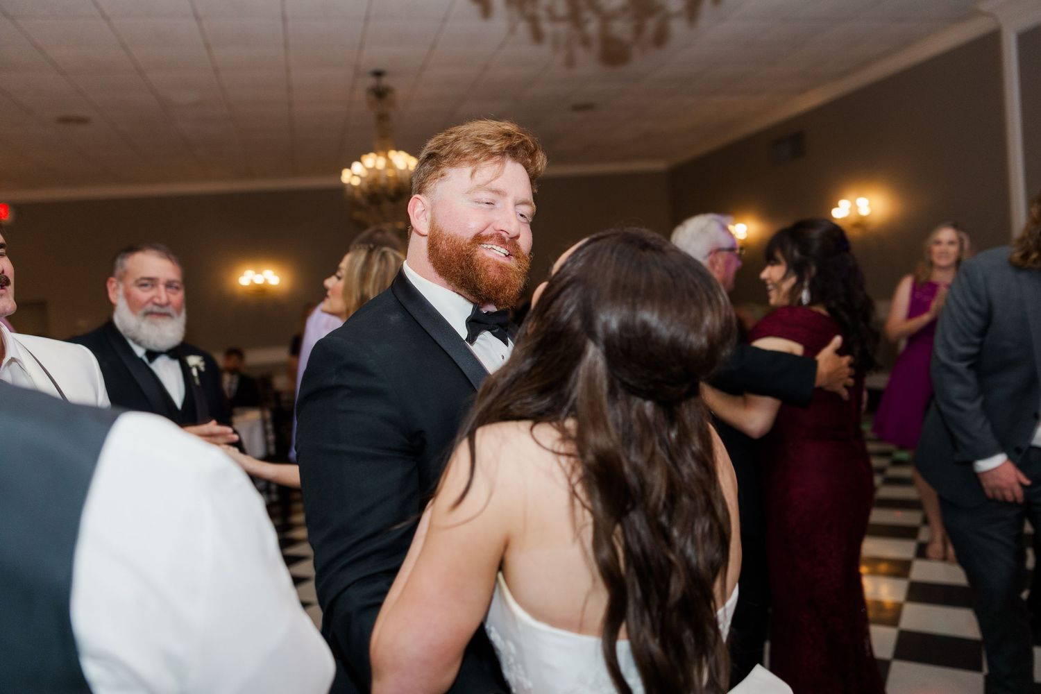 Wedding guests enjoying dances and celebrations at an indoor evening reception.
