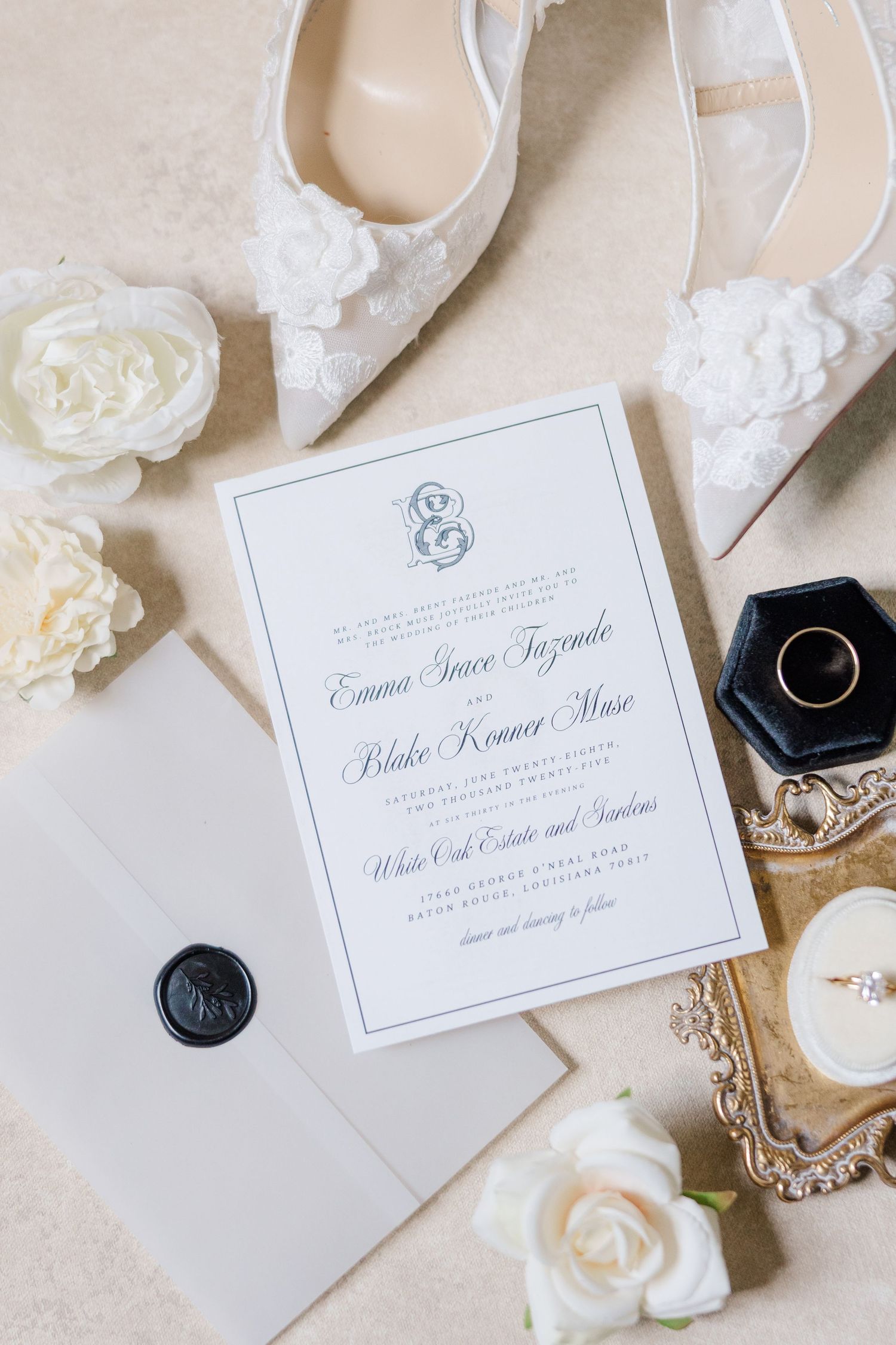 Classic wedding invitations with calligraphy, white roses and black wax seals on cream background.