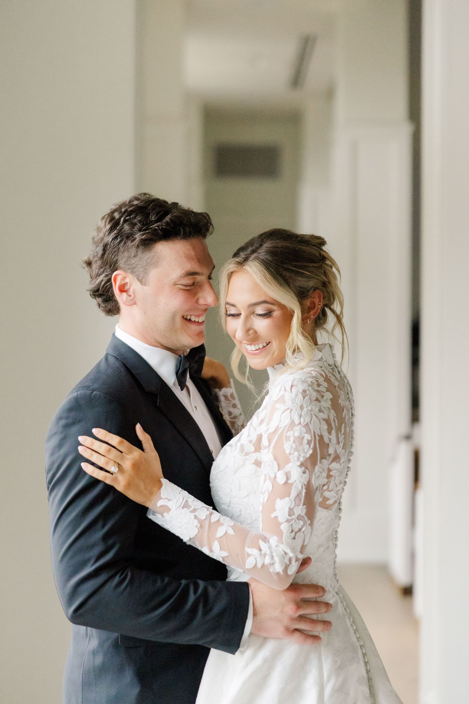 Romantic first look moment between newlyweds sharing an intimate embrace in a bright indoor setting.