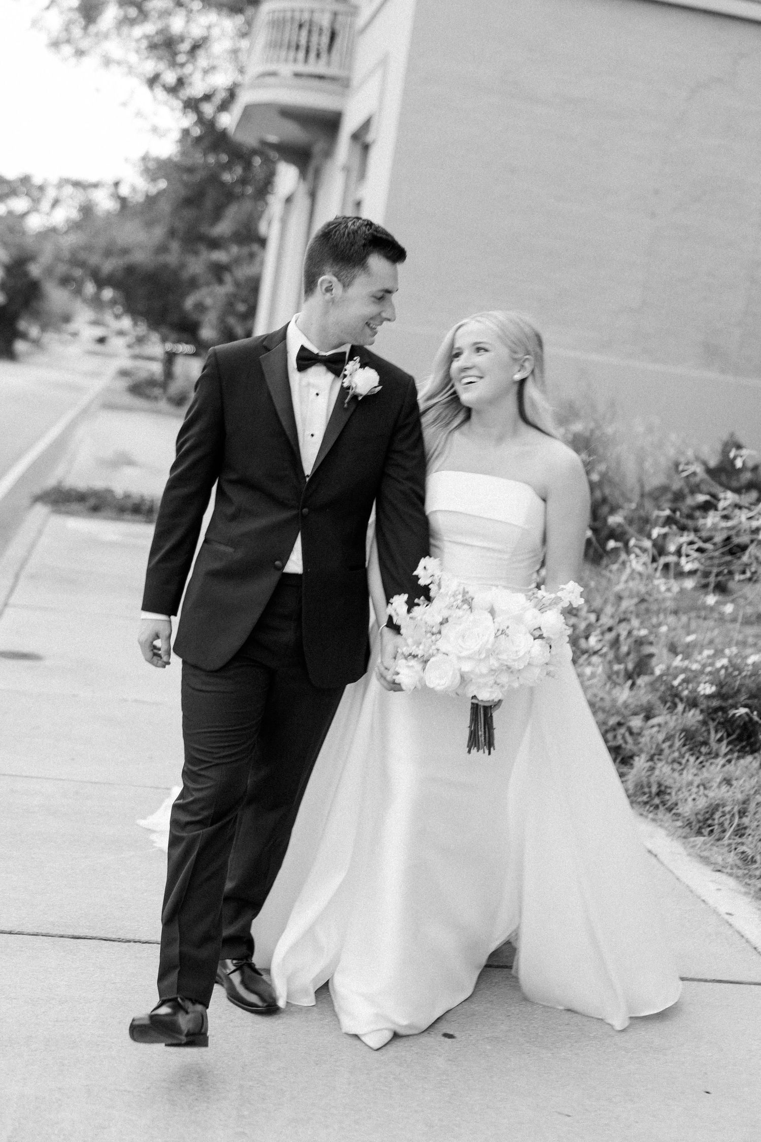 Black and white wedding photos capturing candid moments along garden walkway.