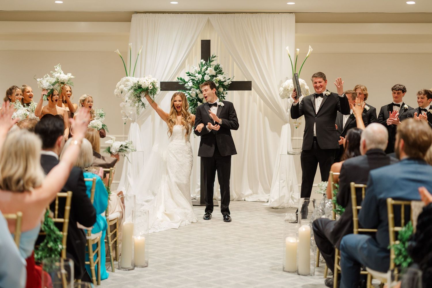 Wedding reception venue with white draping and guests celebrating on the dance floor.