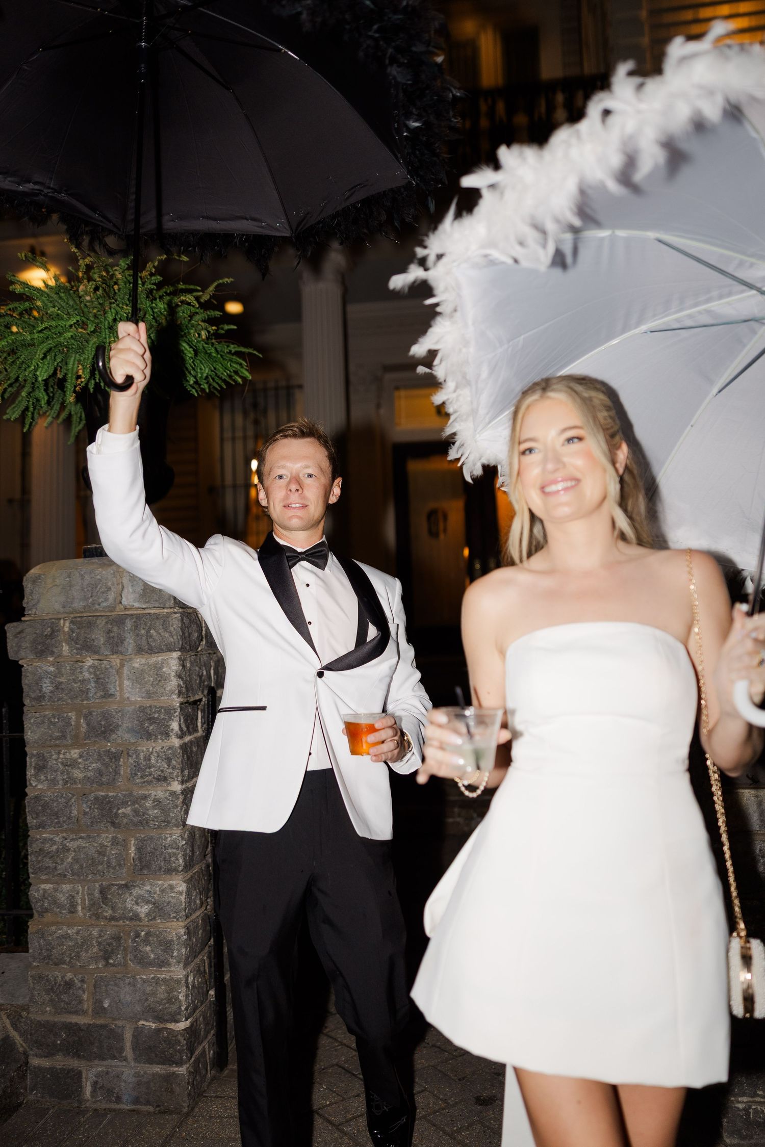 Wedding celebration with white parasols and formal attire during an evening party.