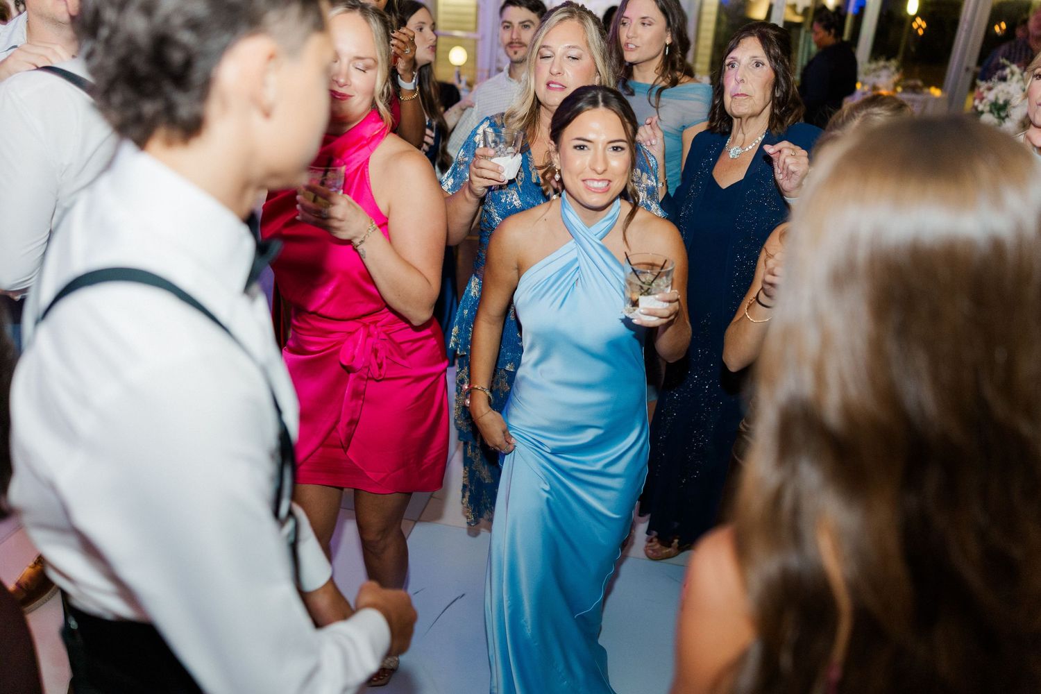 Wedding reception dance floor filled with guests in vibrant dresses enjoying the celebration.