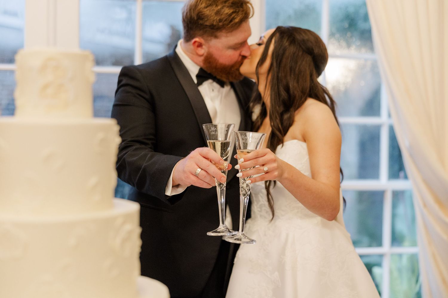 Newlyweds share champagne toast at elegant indoor reception.