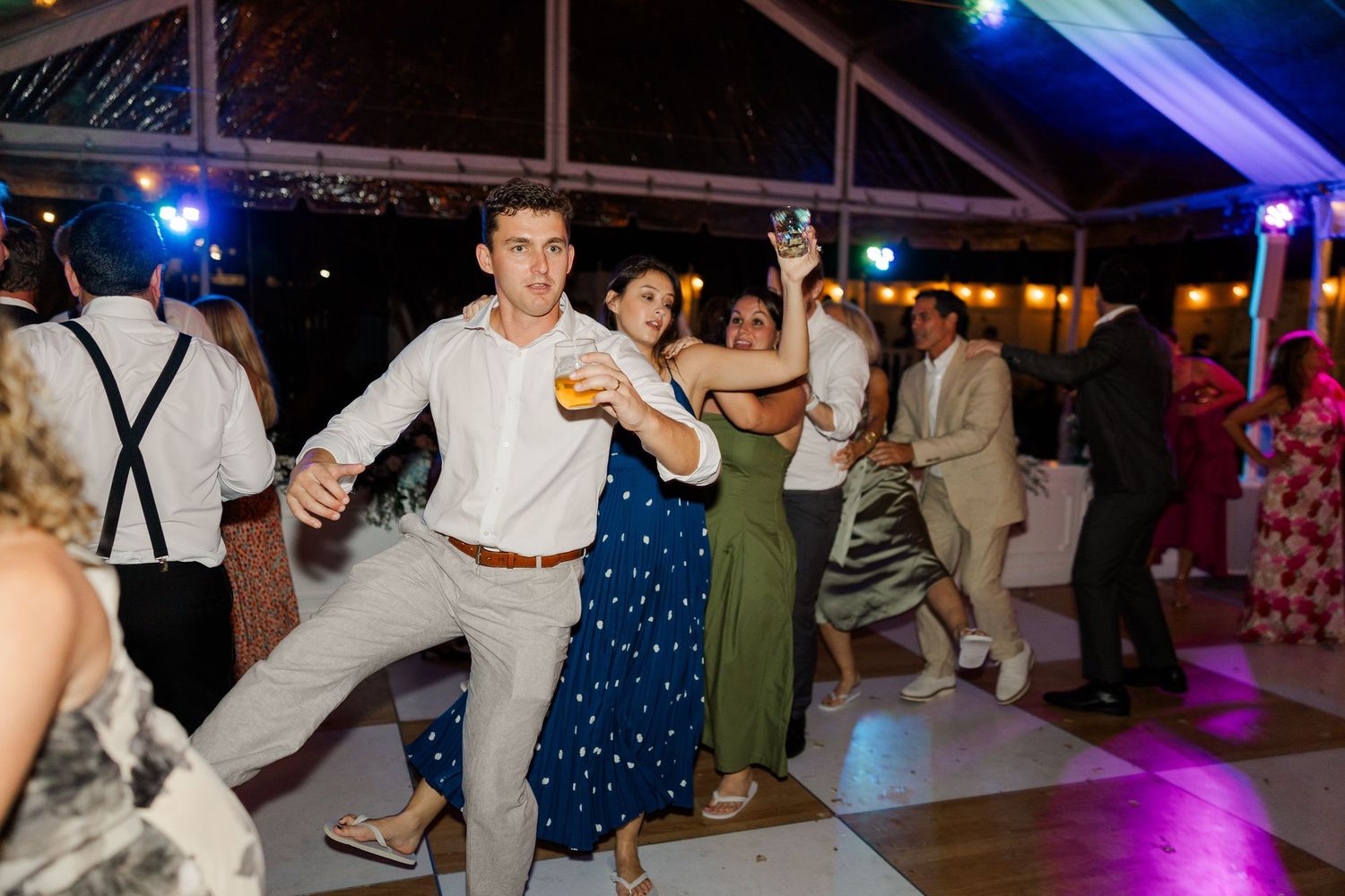 Wedding reception dance party with guests celebrating under blue lighting.