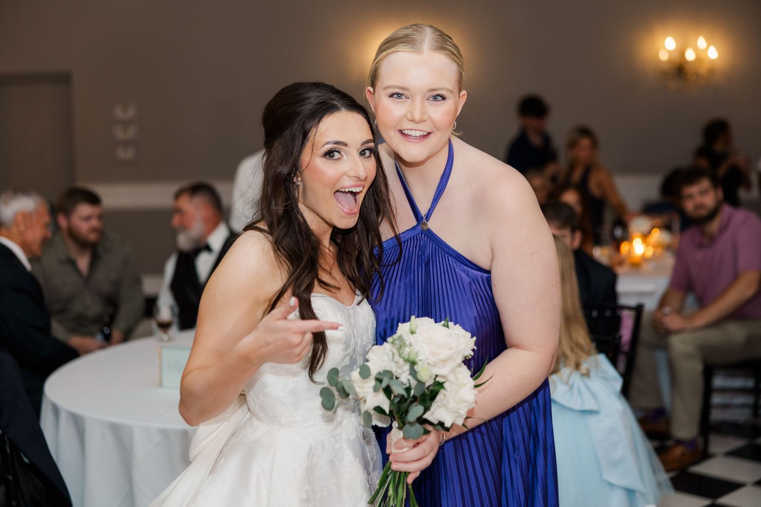 Wedding reception celebration with guests dancing under elegant chandeliers.