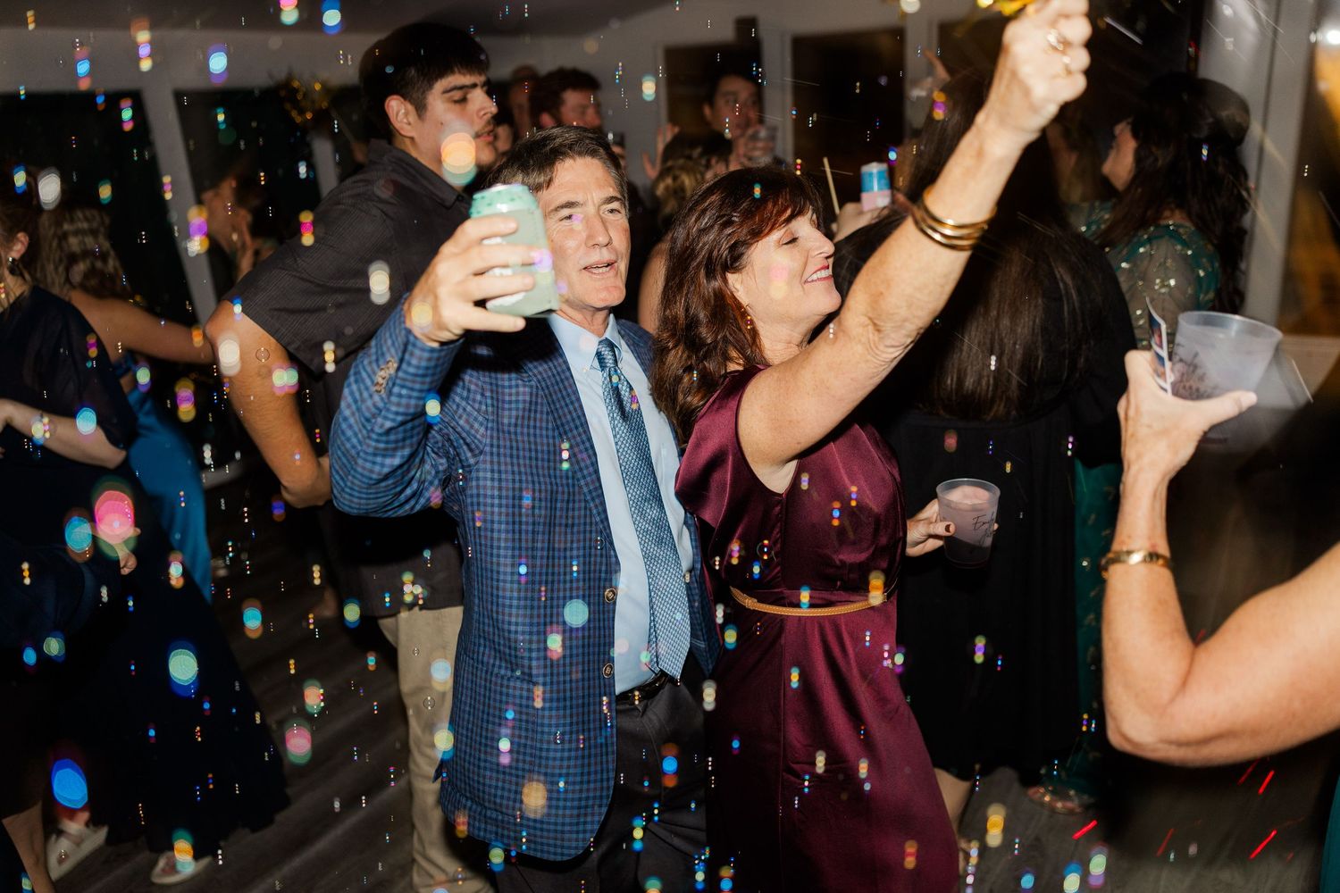 Lively party scene with guests dancing under blue lighting and confetti.