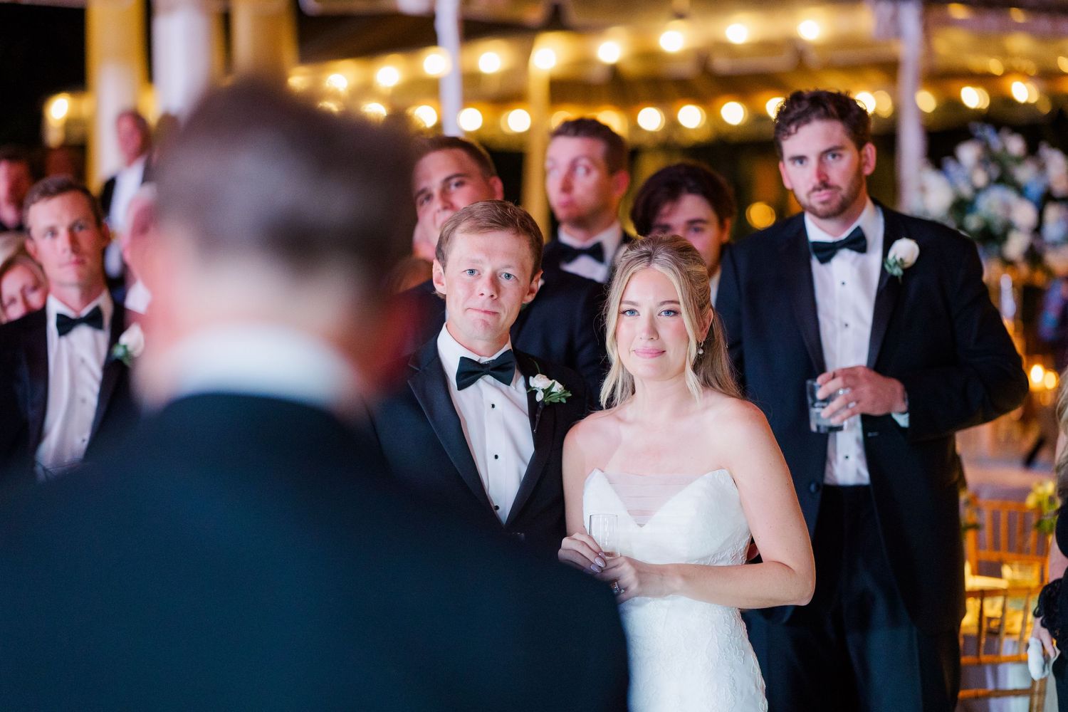 Formal wedding reception with guests dancing under ambient lighting.