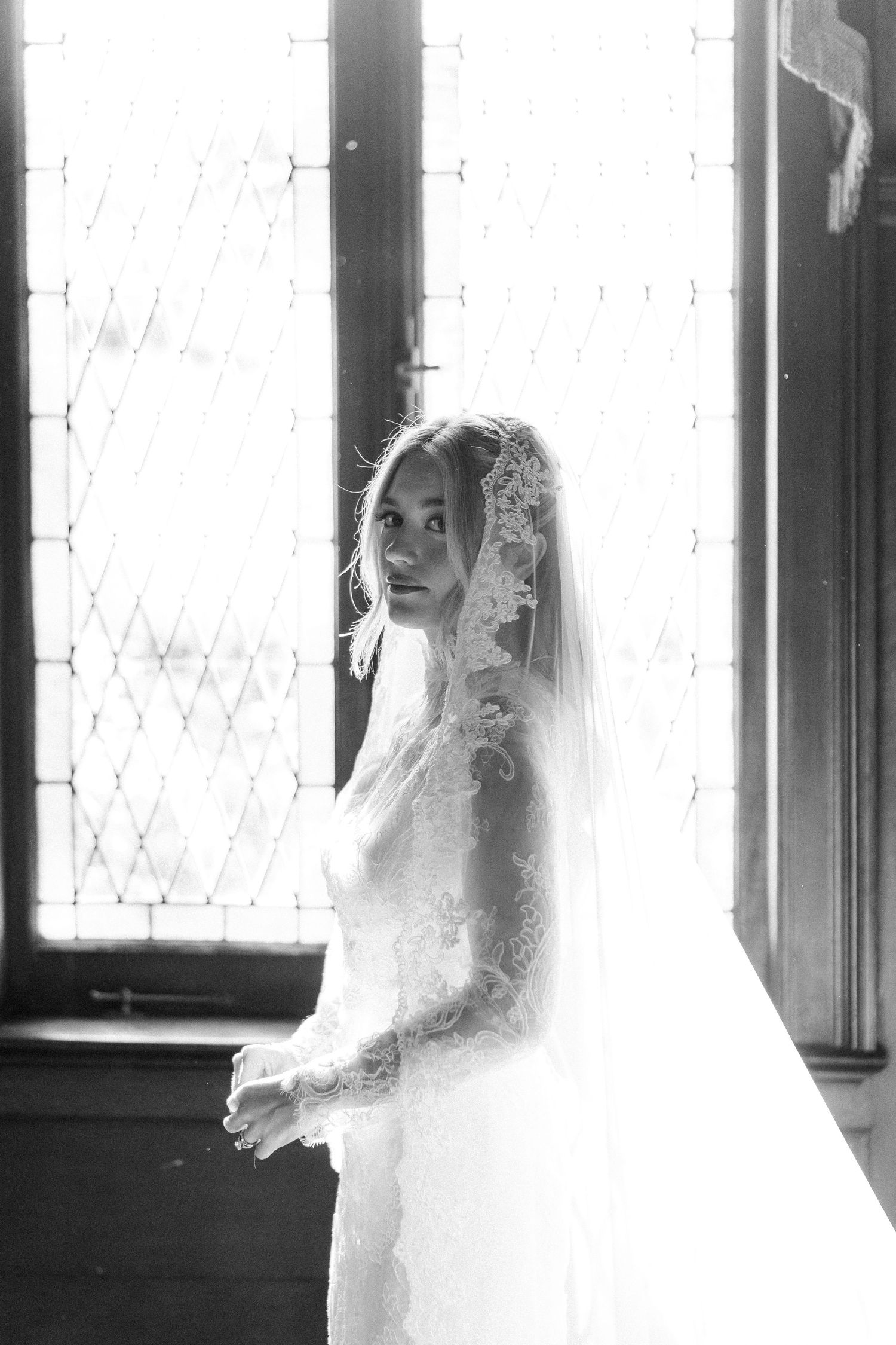 Ethereal bridal portraits in black and white with dramatic window lighting.