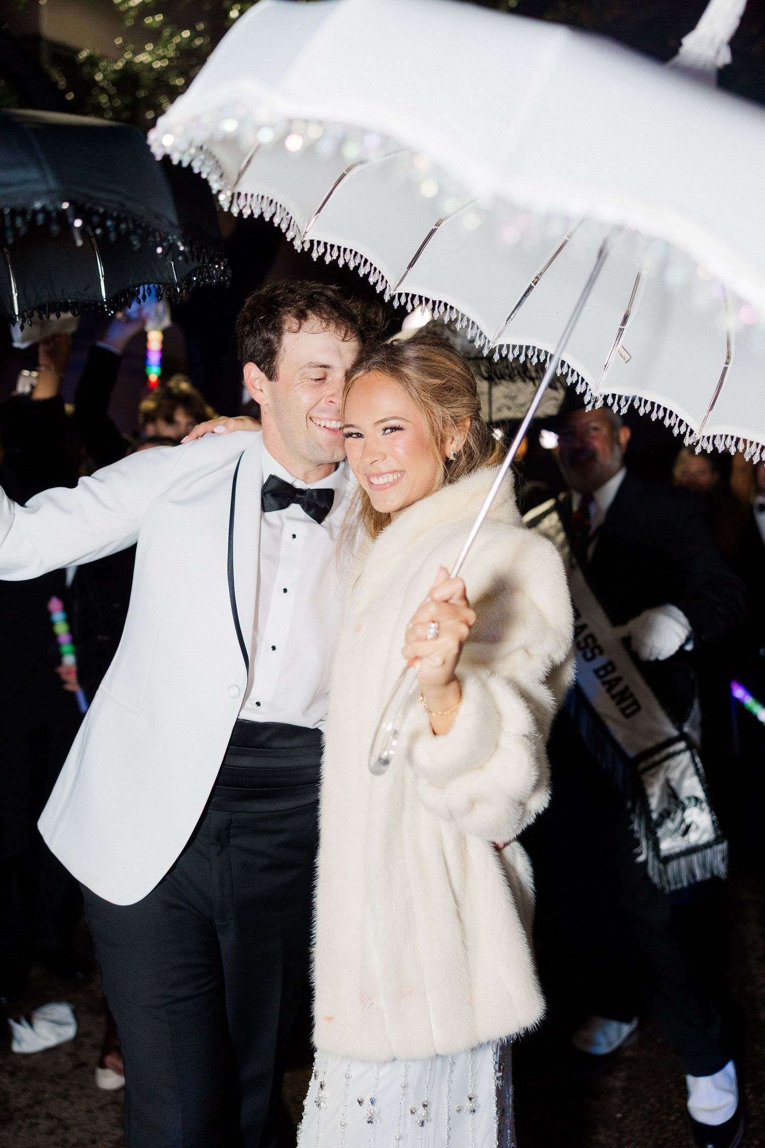 Couple sharing romantic moment under white lace parasol at nighttime celebration.