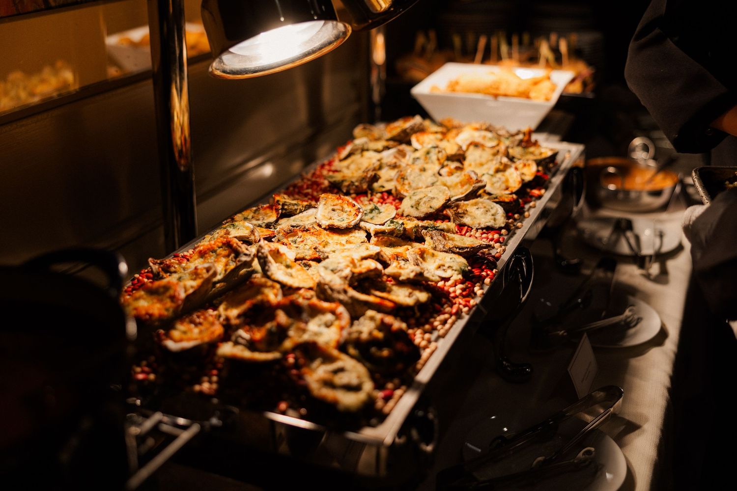 Catering display of grilled meats and appetizers under warm lighting.