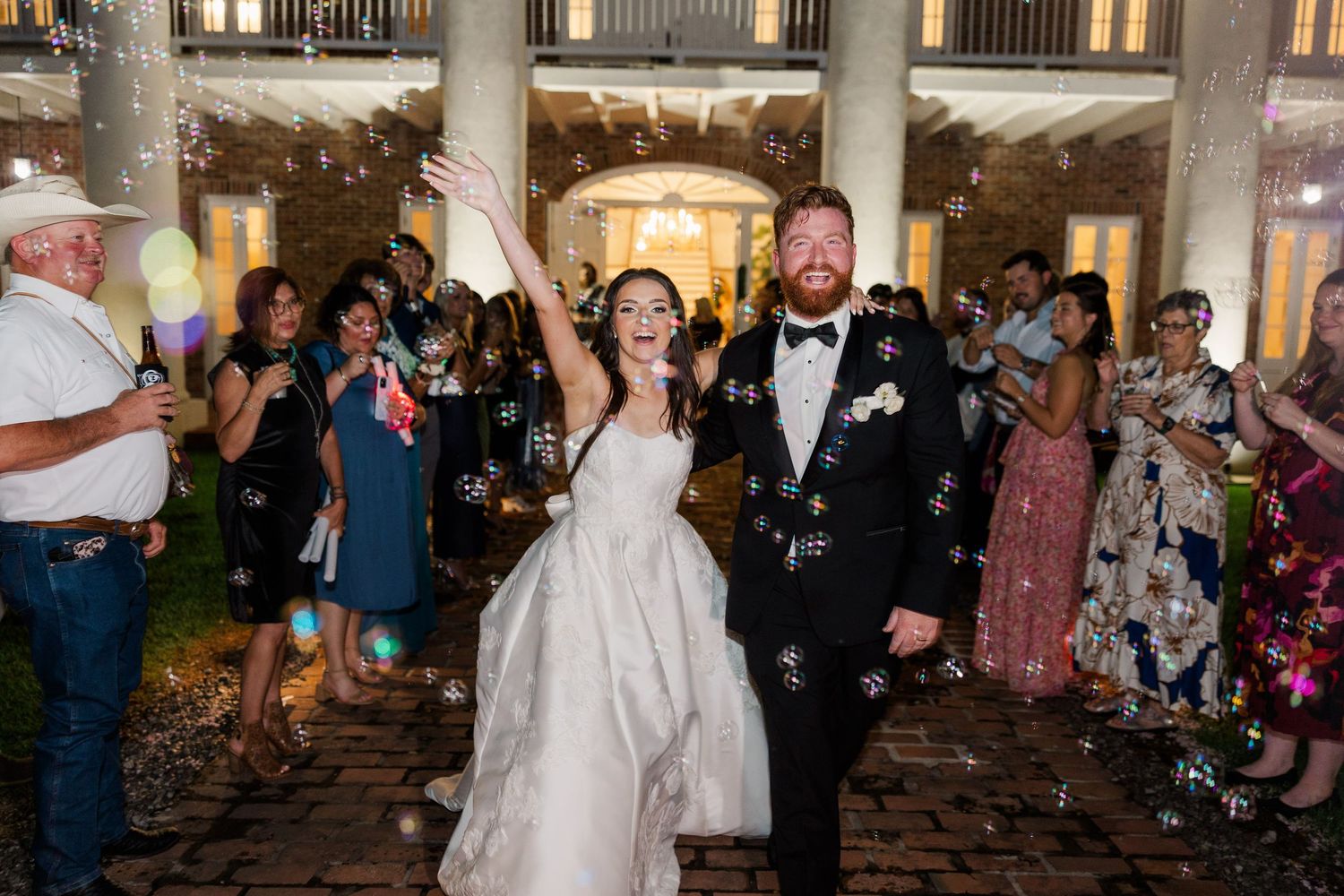 Newlyweds celebrate with guests during their first dance at an elegant indoor reception.