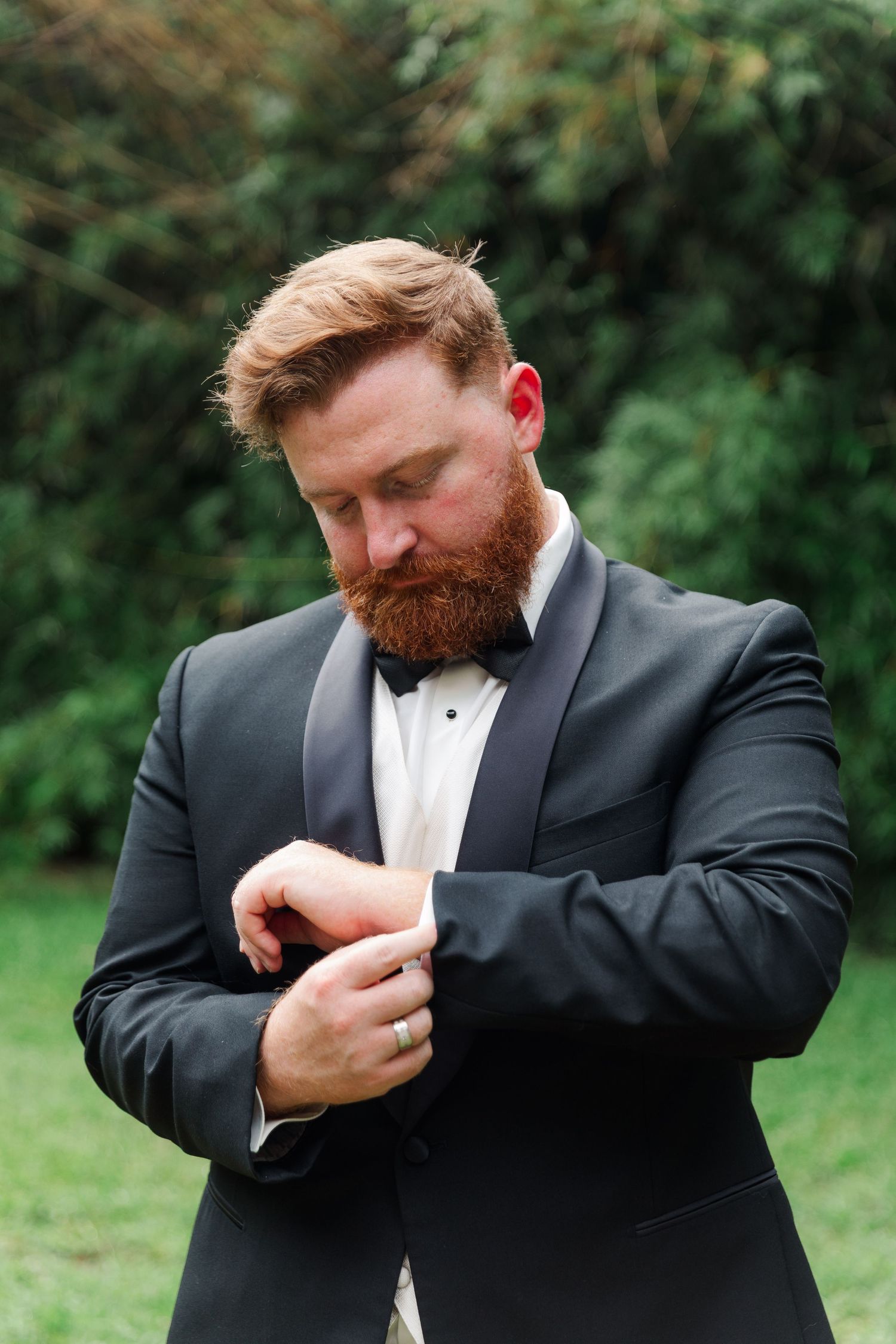 Groom in black suit adjusts his sleeve cuffs in a series of candid outdoor photos.