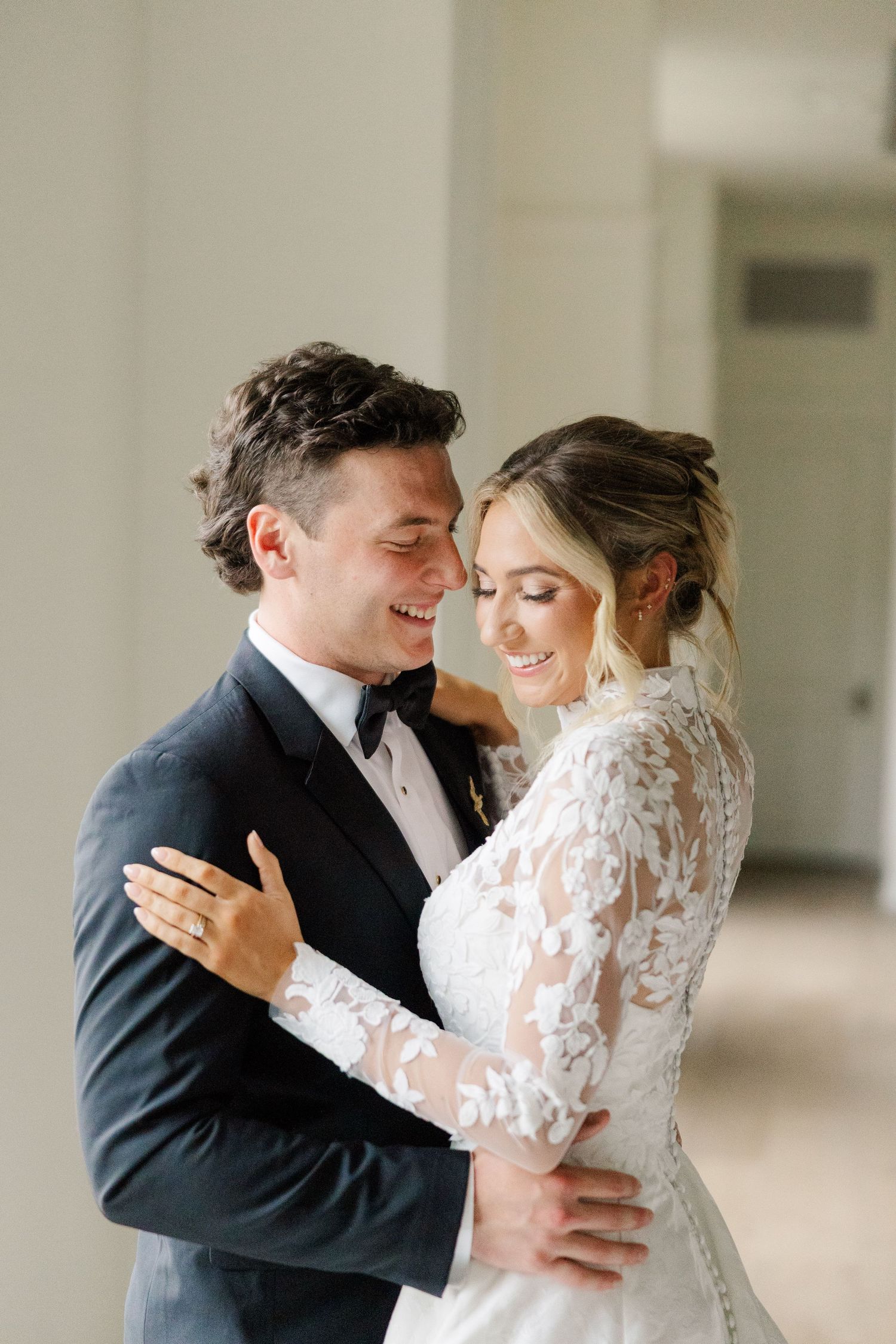 Intimate wedding photos capturing sweet embraces between newlyweds against white interior backdrop.