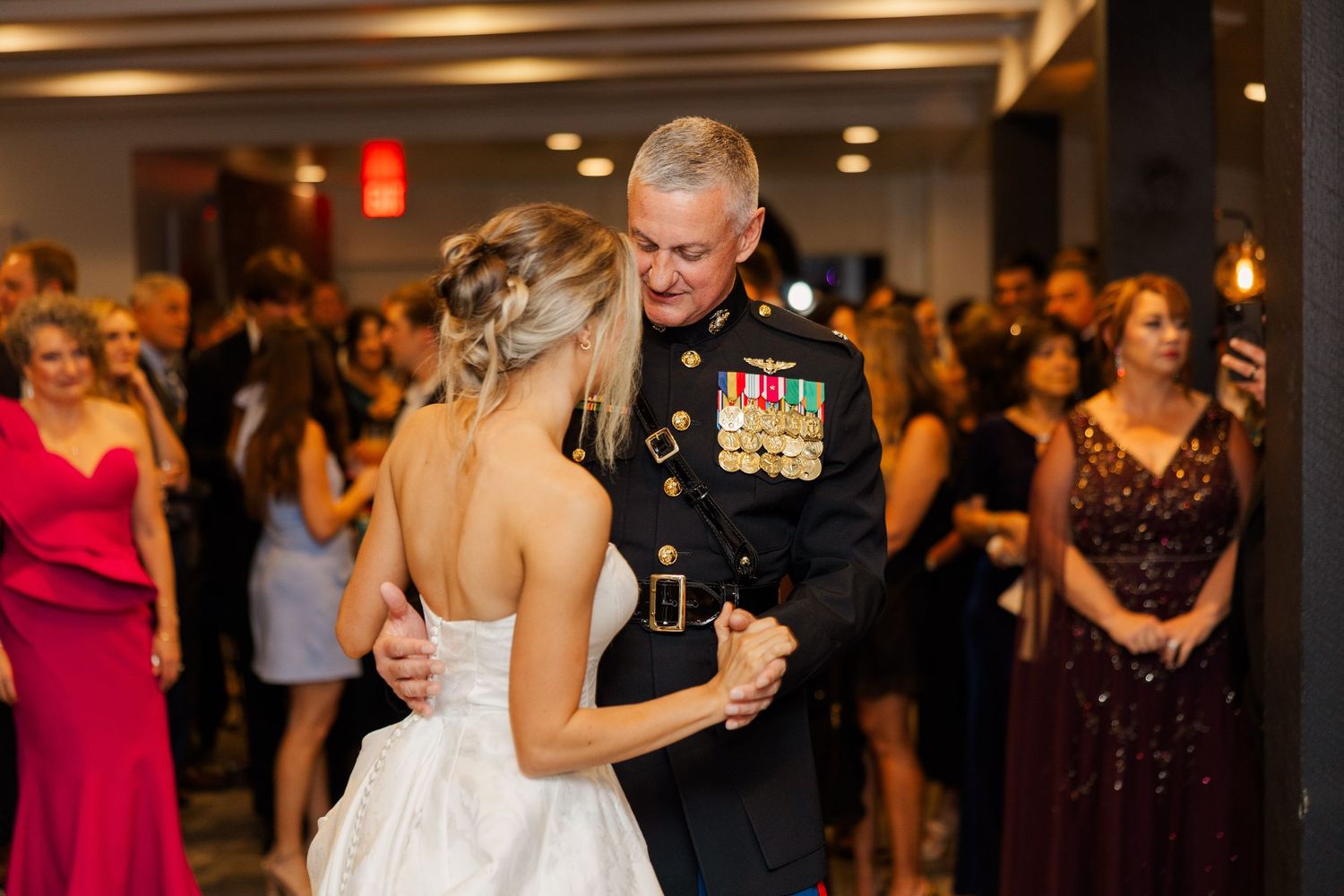 A touching dance moment captured during a wedding reception with guests looking on.