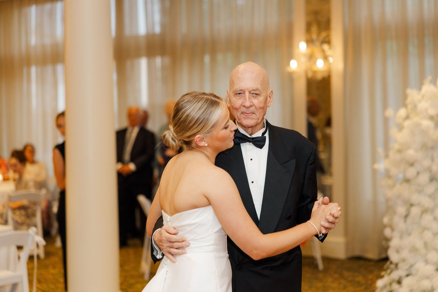 Elegant ballroom dance sequence between wedding couple with warm lighting.