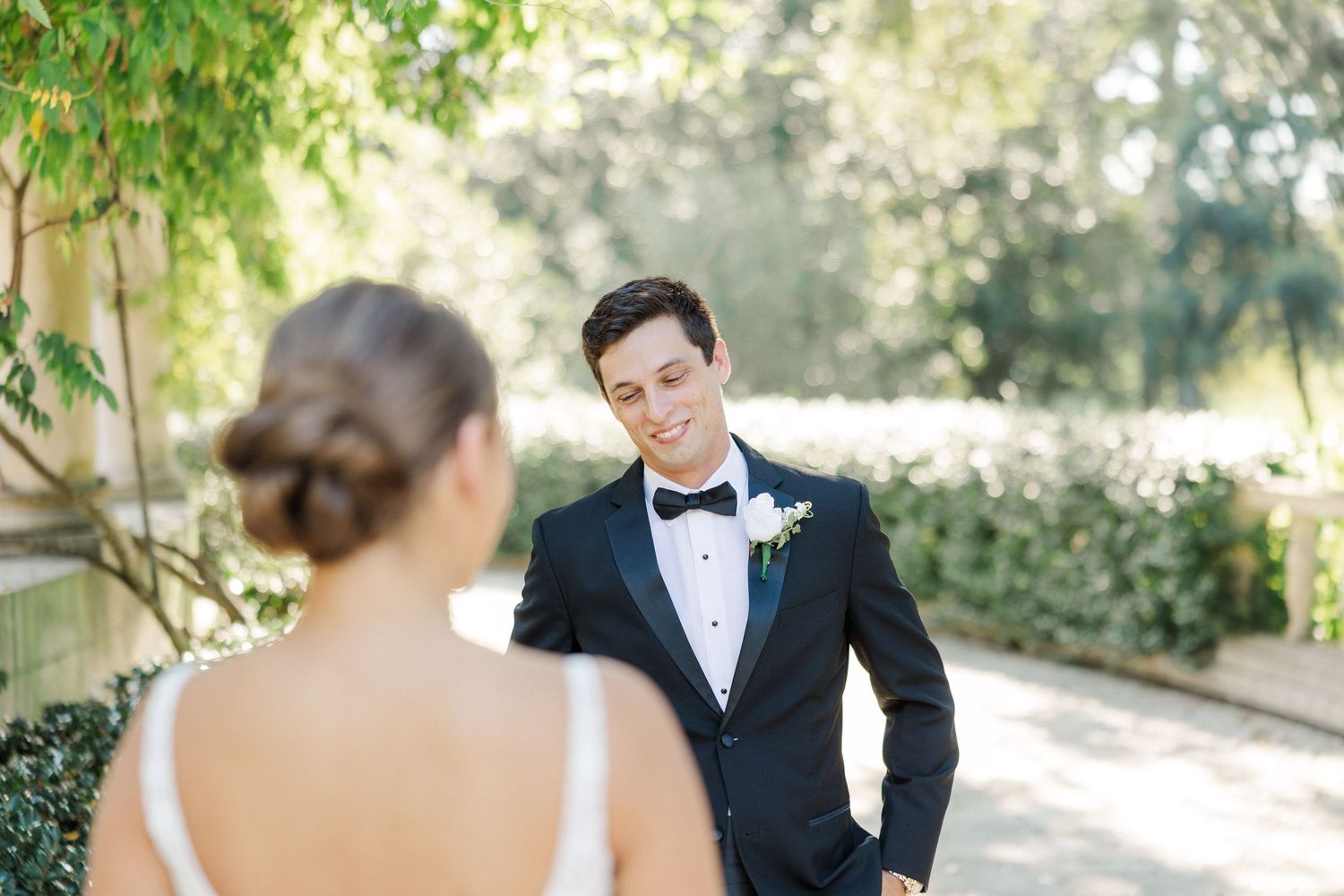 Couple shares intimate moments during outdoor wedding photoshoot in a sunlit garden setting.
