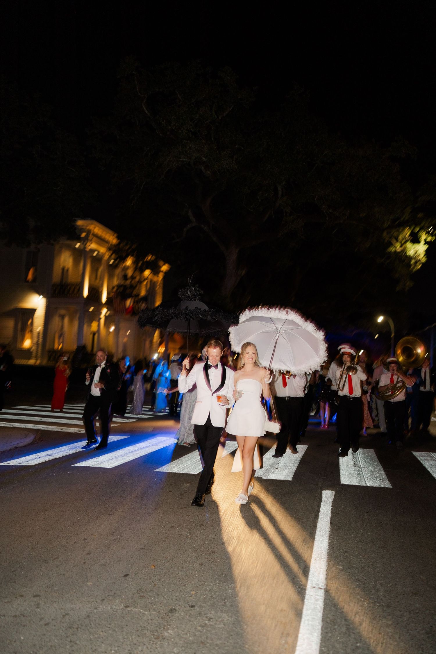Wedding guests walk along illuminated pathways during an evening outdoor celebration.