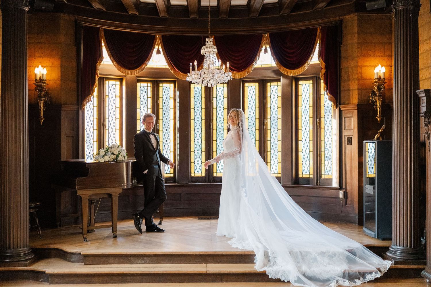Wedding photos captured in a grand historic venue with dramatic chandeliers and dark wood details.