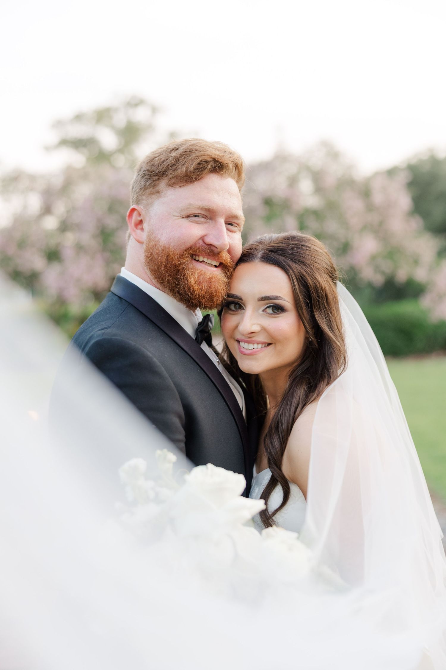 Romantic wedding portraits in a blooming spring garden with soft natural lighting.