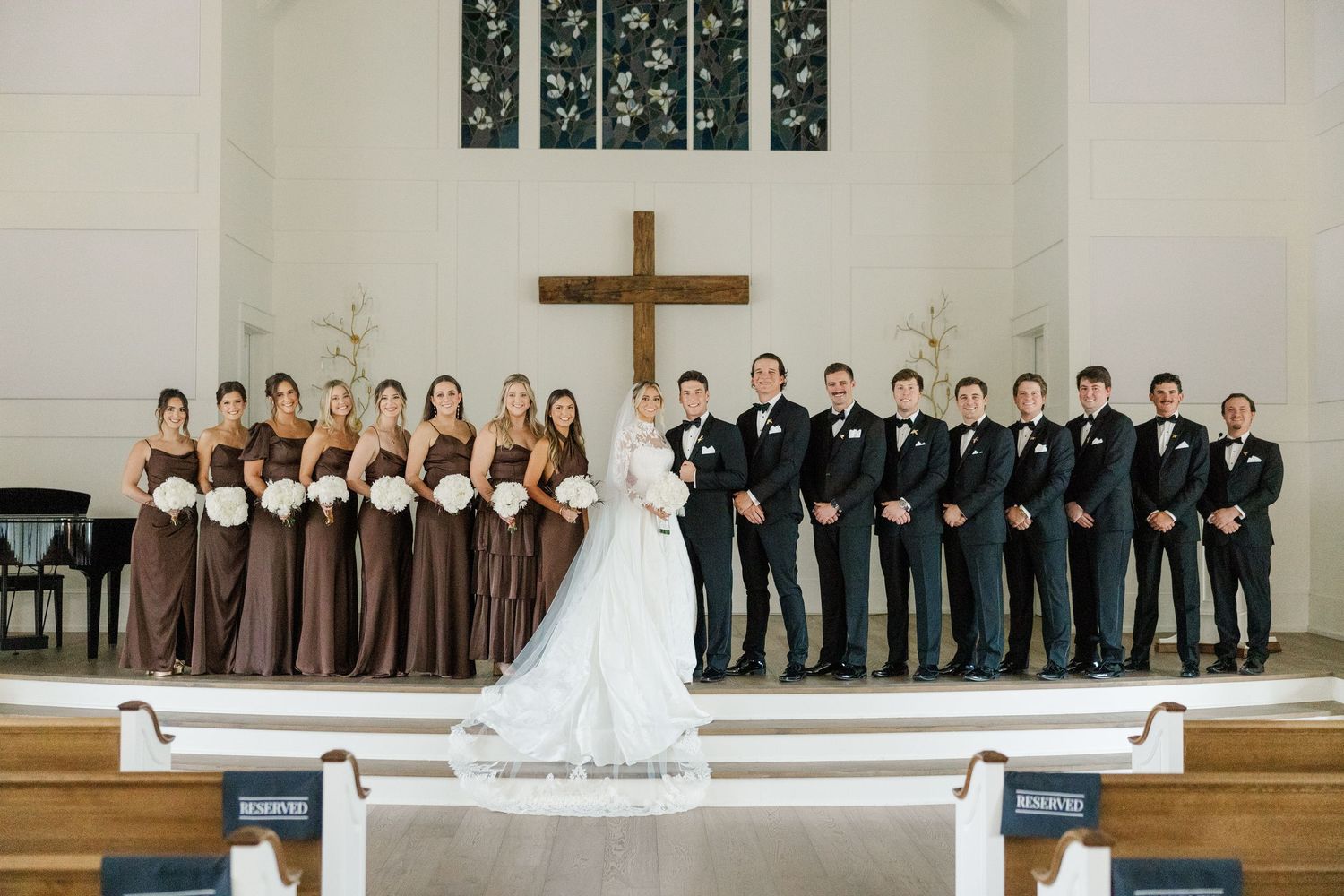 Wedding ceremony setup in white church with wooden cross and pews.