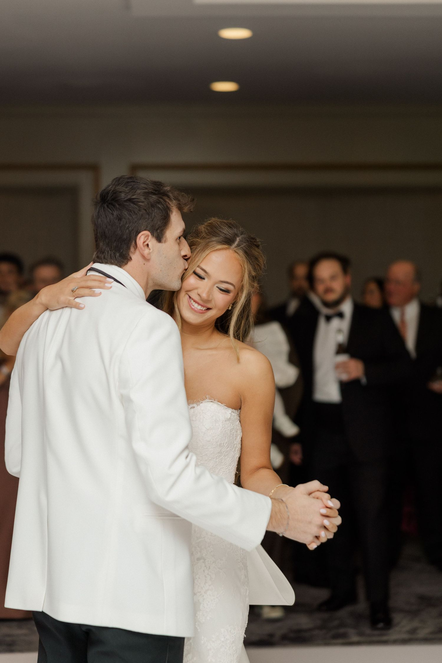 A couple shares their first dance at an elegant indoor wedding reception.