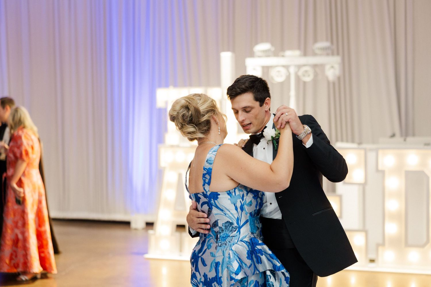 Wedding reception dance floor with blue uplighting and white draping creates an elegant party atmosphere.