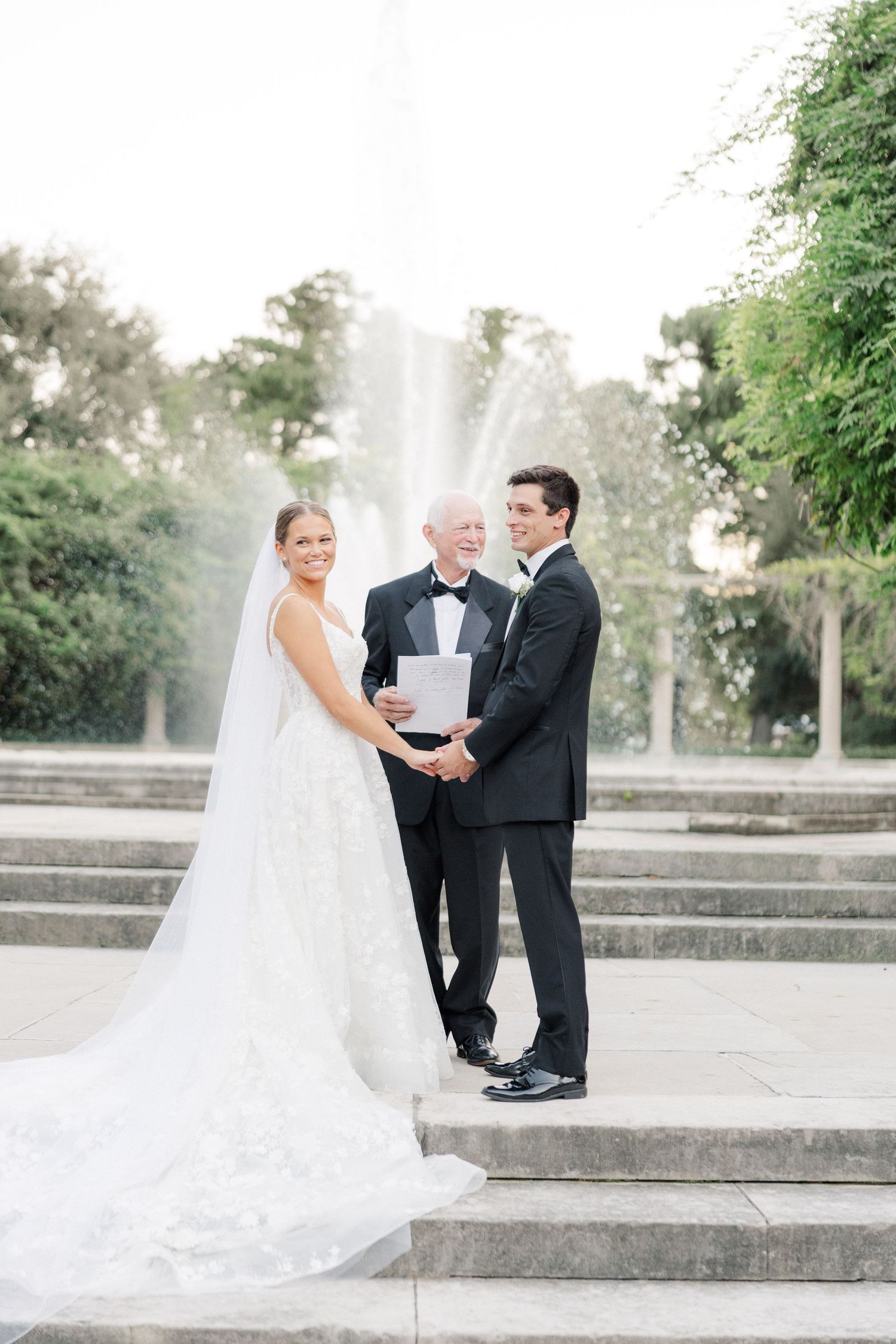 Outdoor wedding ceremony on stone steps with flowing white wedding gown.