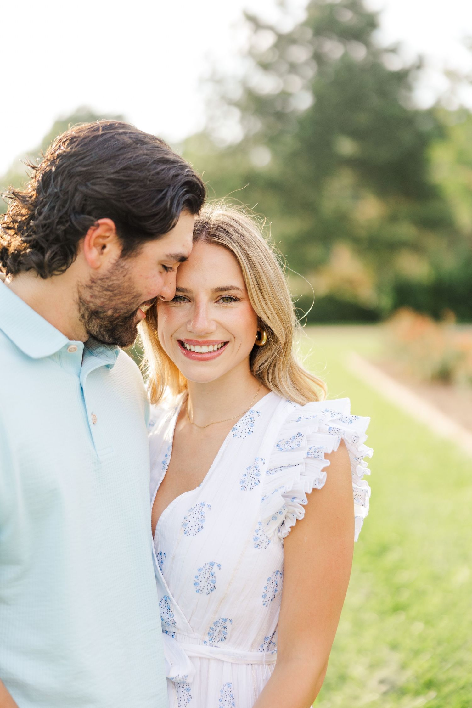 A close-up portrait of a couple sharing an intimate moment in a garden setting with soft natural lighting.
