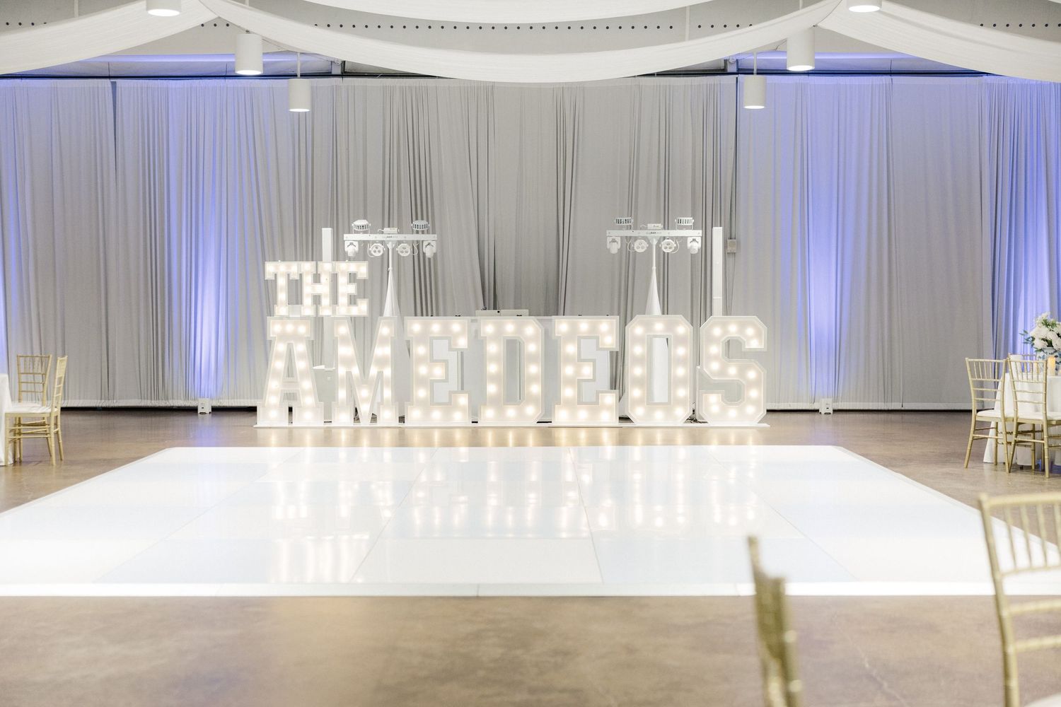 Elegant white wedding reception venue with crystal chandeliers and draped fabric creating a romantic atmosphere.