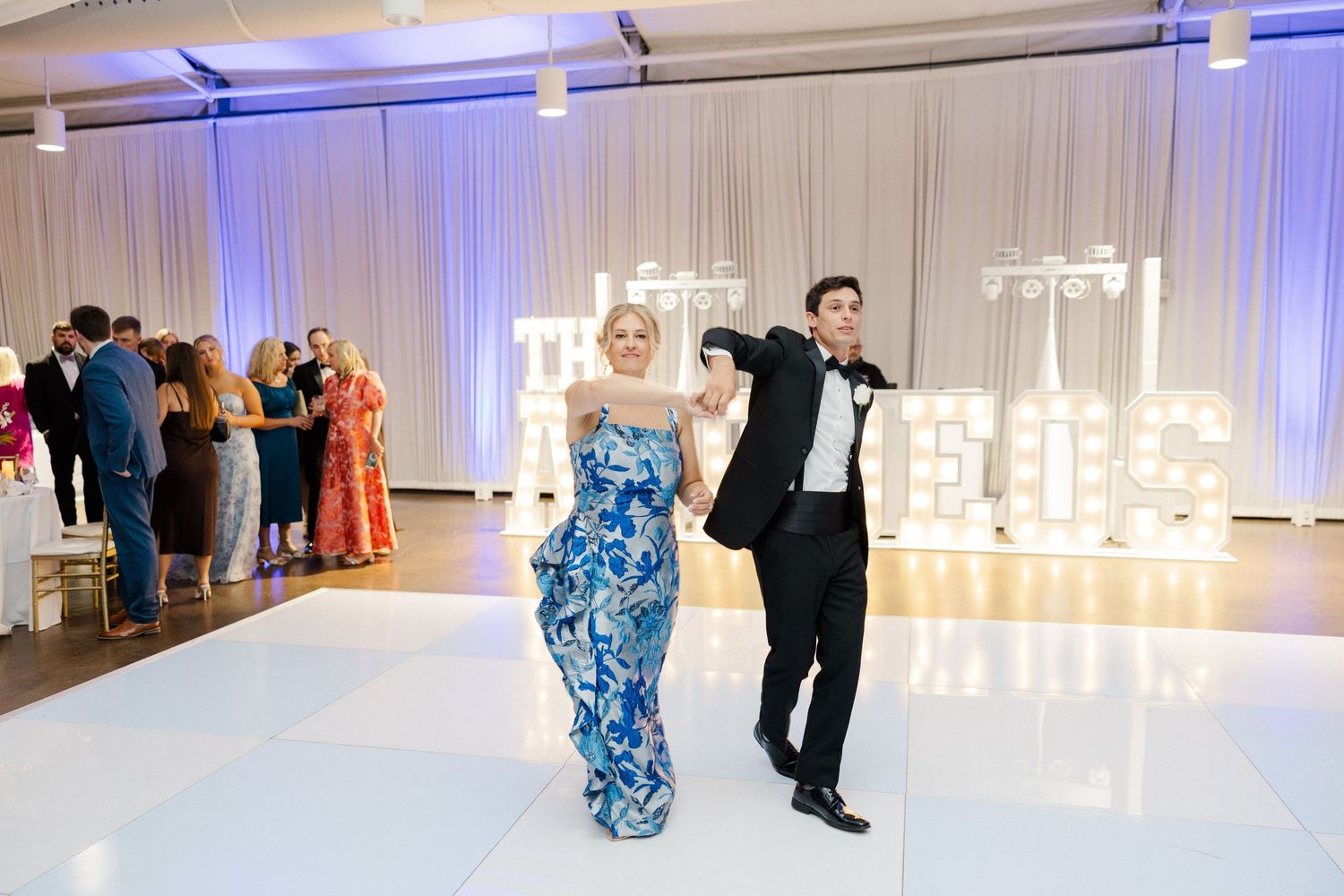 Wedding reception dance floor with blue uplighting and illuminated marquee letters.