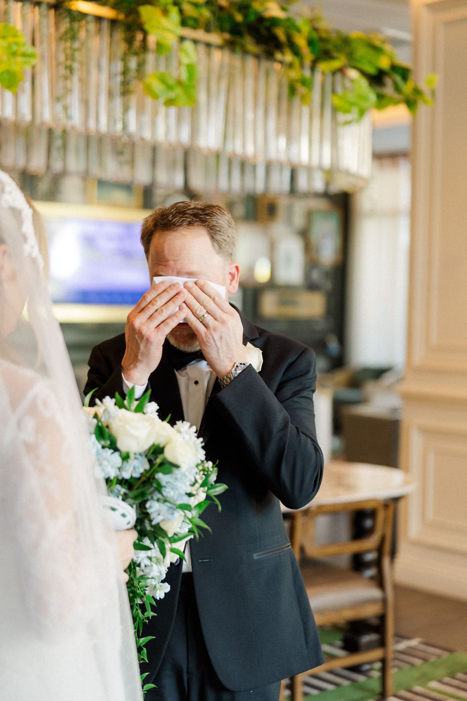 Emotional first look moment captured during wedding ceremony with white floral bouquet.
