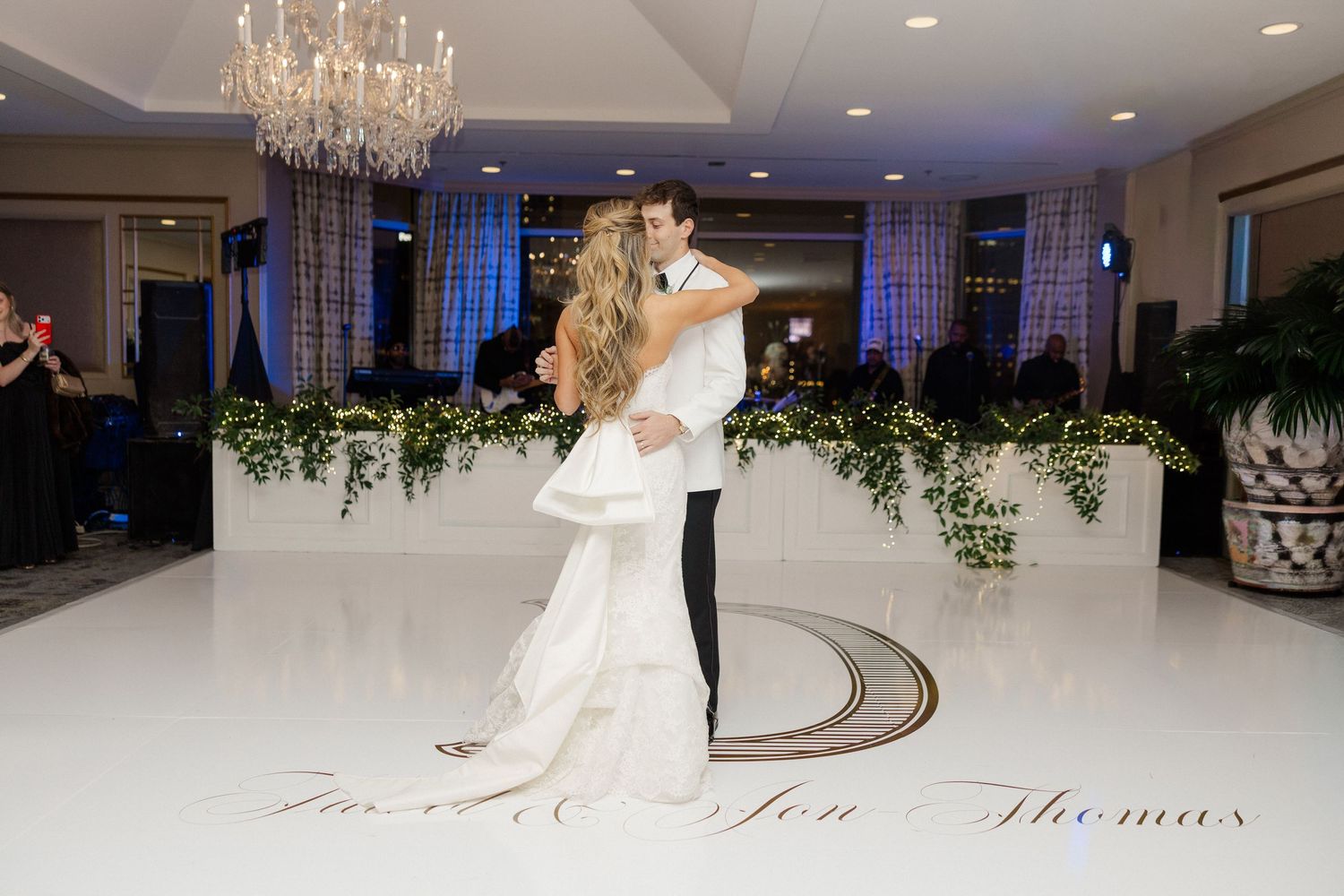 Elegant ballroom wedding reception with crystal chandelier and white decor.