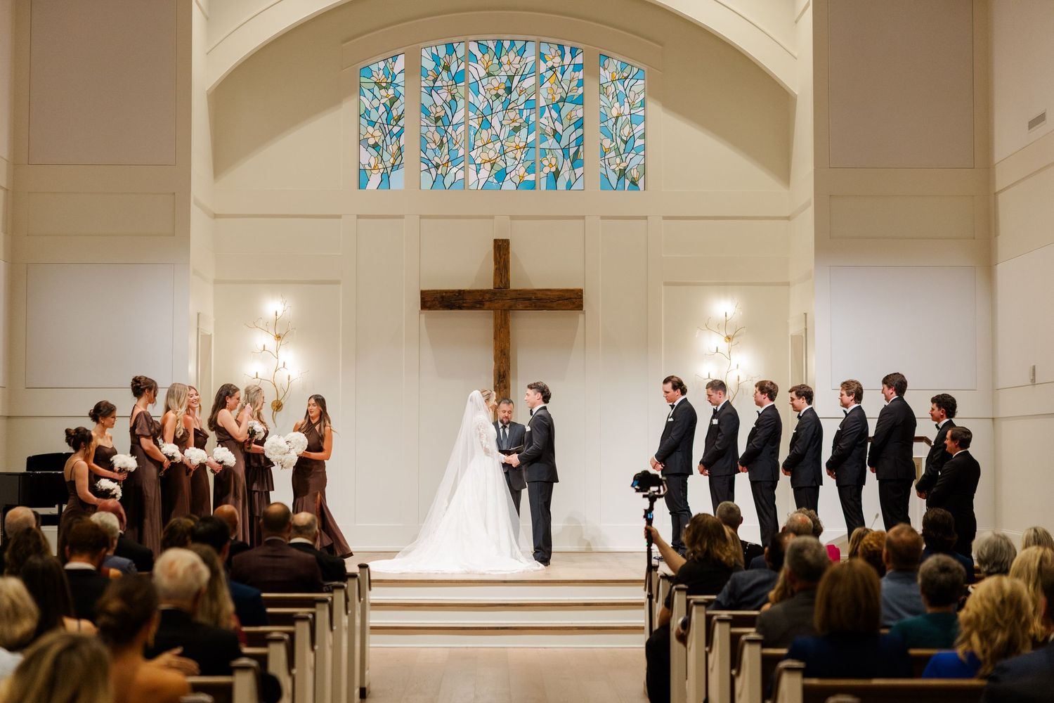 A traditional church wedding ceremony with guests seated in wooden pews under arched ceilings.