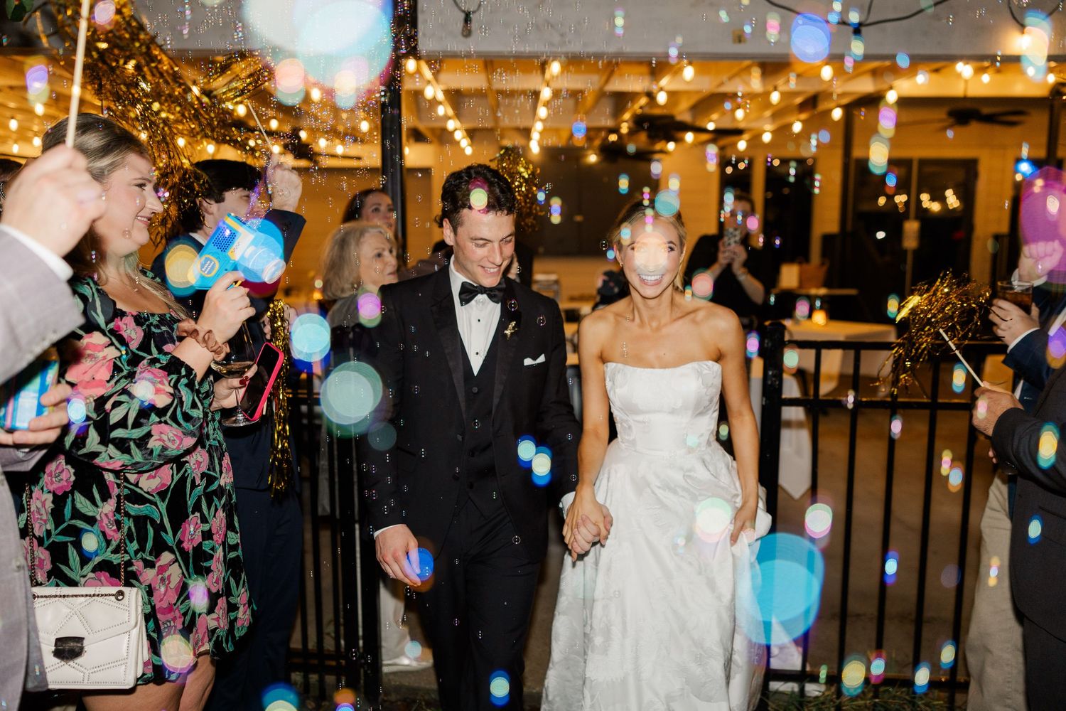 Wedding celebration with guests blowing bubbles during an evening outdoor reception.
