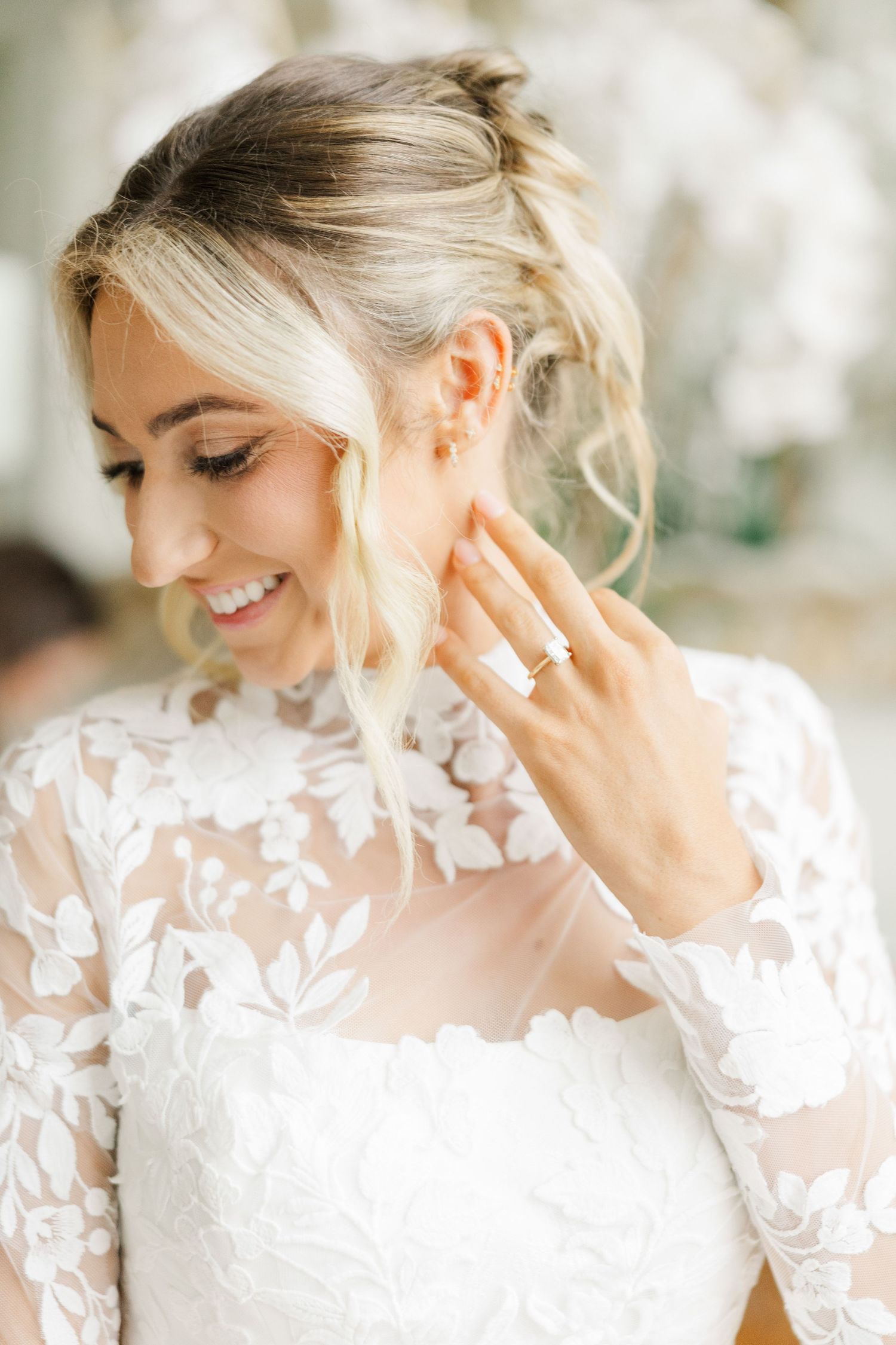 Close-up details of a bride's delicate lace wedding dress and elegant updo hairstyle in natural light.
