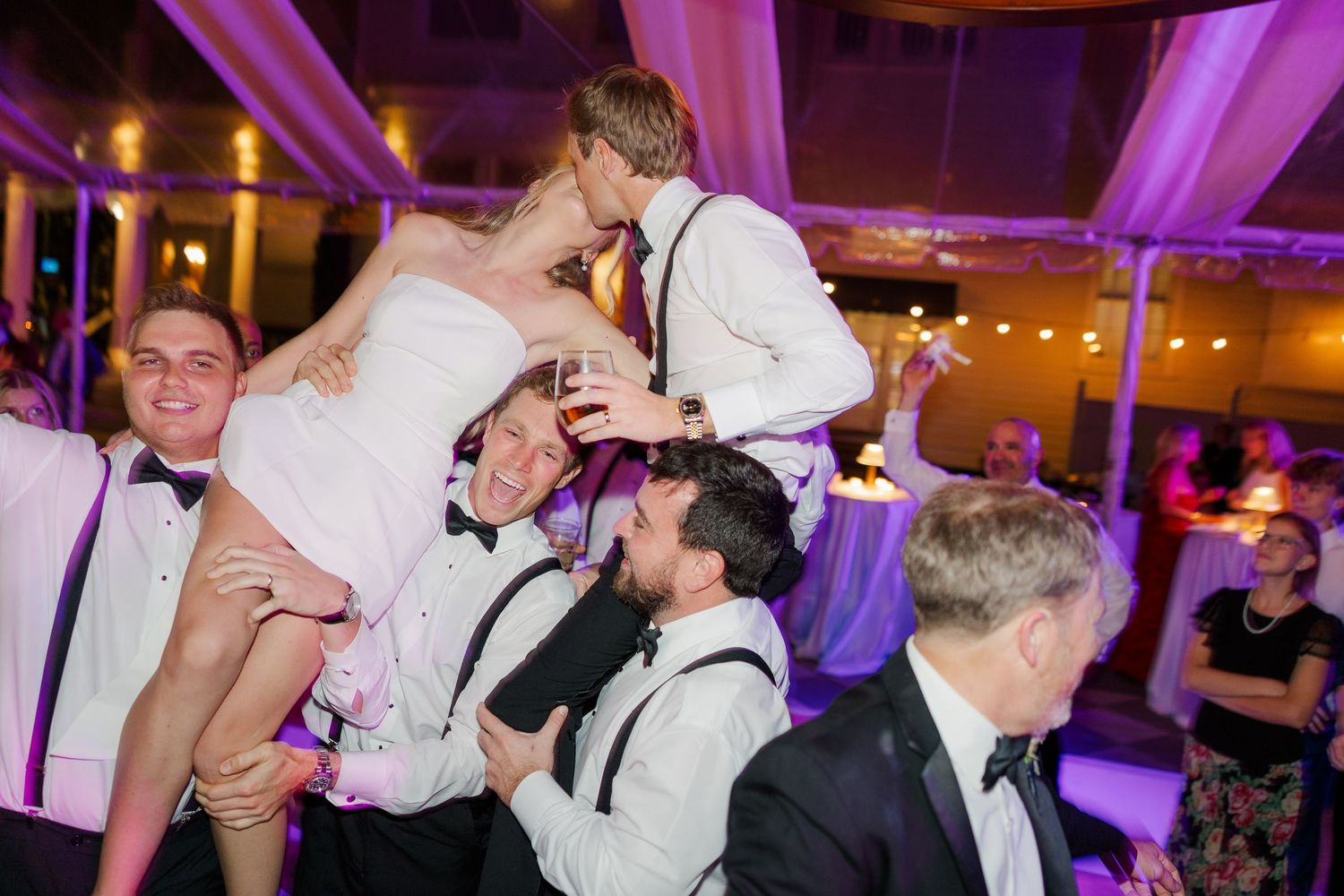 Energetic wedding reception dance floor moment with purple lighting and festive atmosphere.