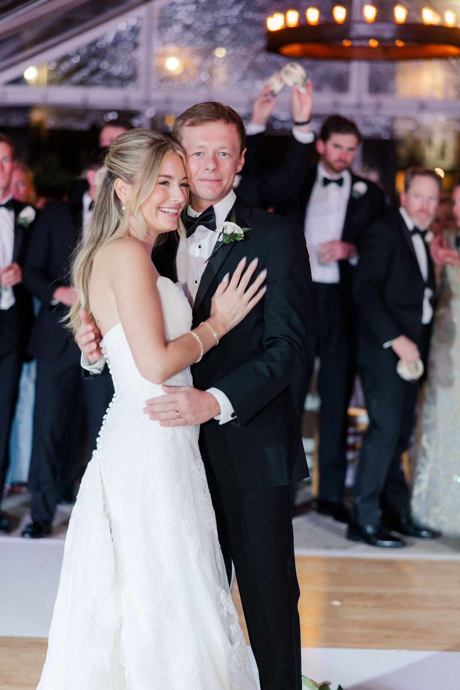 Wedding couple sharing their first dance under romantic lighting at indoor reception.