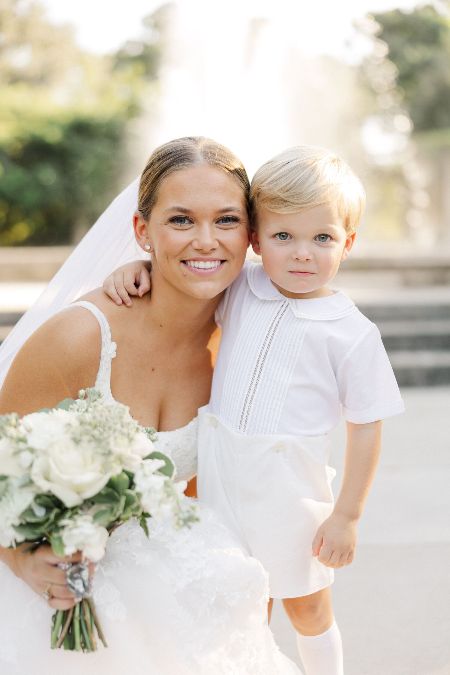 Sweet candid moments between bride and young ring bearer in white attire.